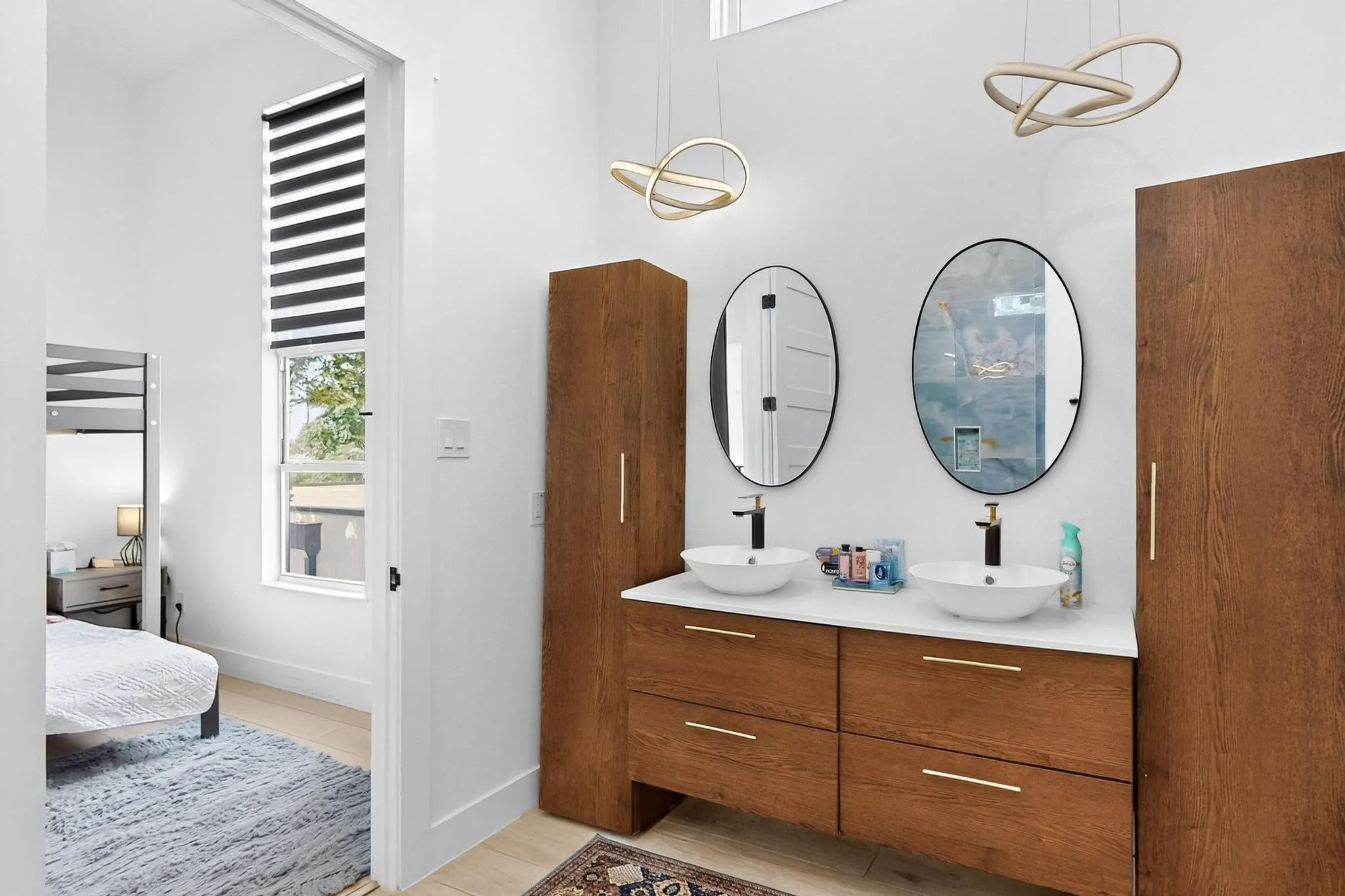 Dual vessel sinks with wall-mounted faucets set on a wood-finish vanity with white countertop