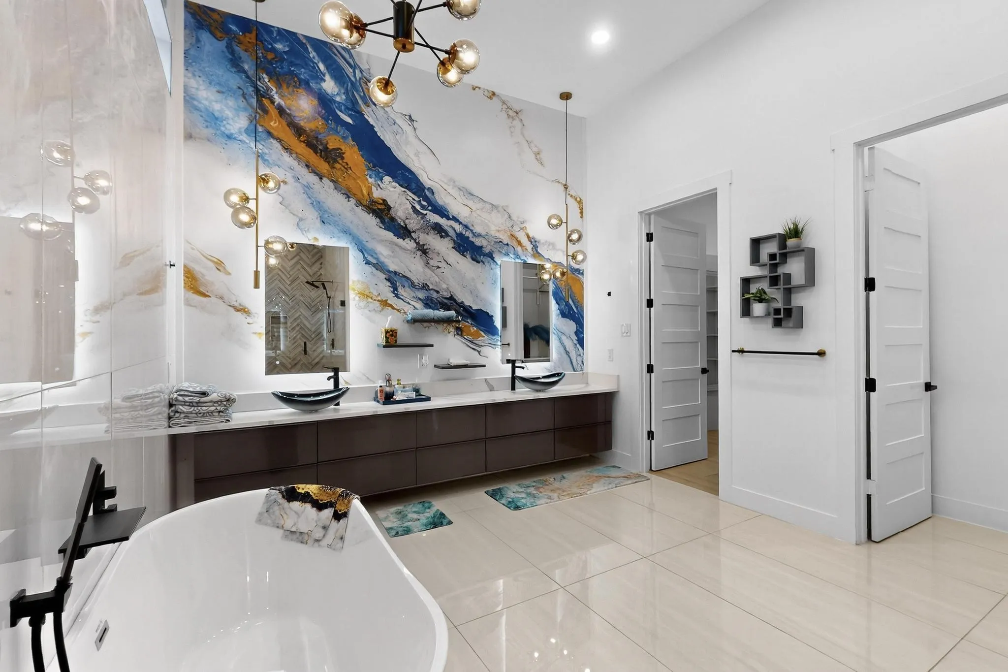 Bathroom featuring a freestanding soaking tub, dual floating vanities with vessel sinks, a statement wall with abstract art, and contemporary lighting fixtures