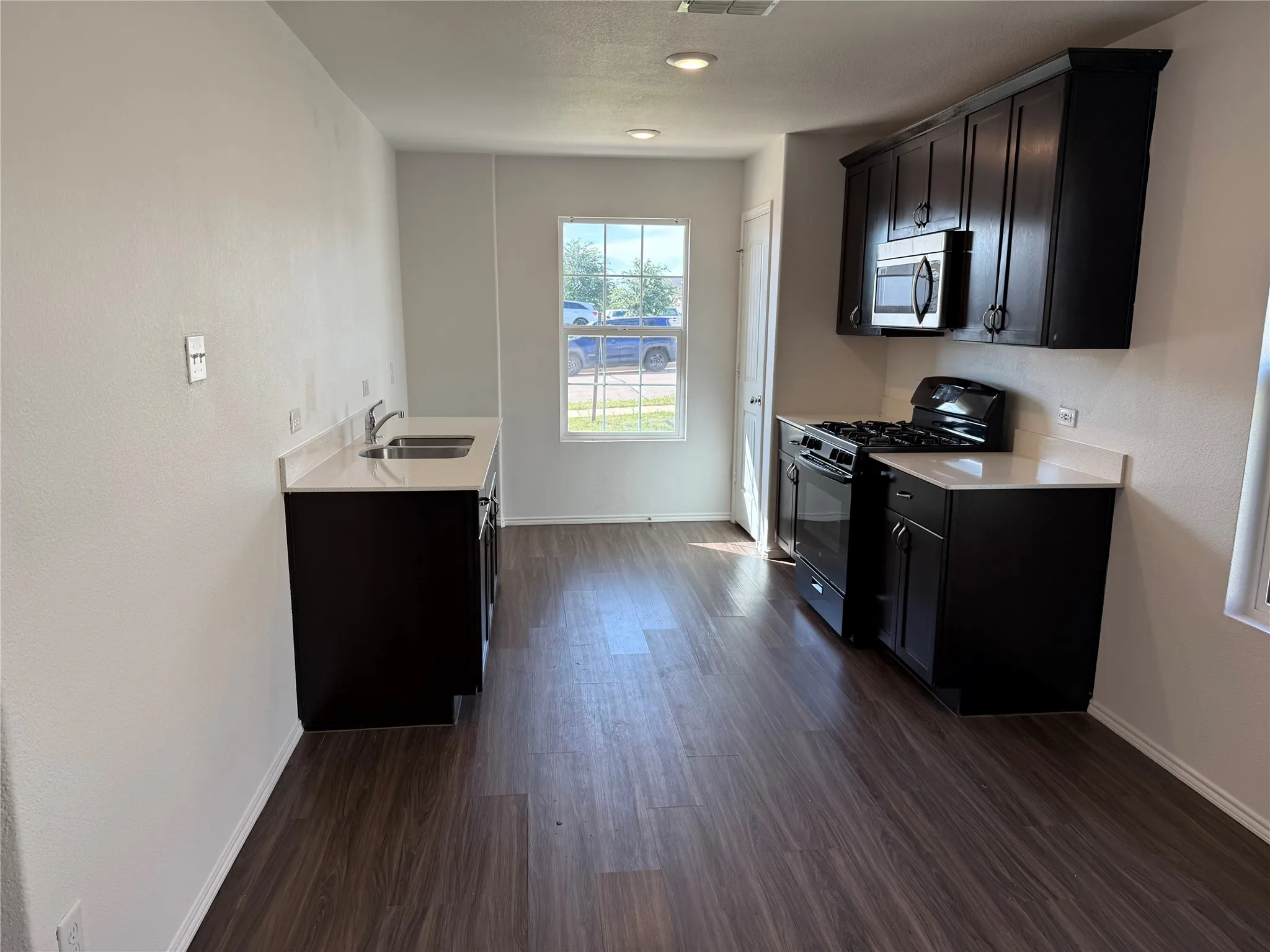 Kitchen featuring dark wood-finish cabinetry, white countertops, and wood-finish flooring