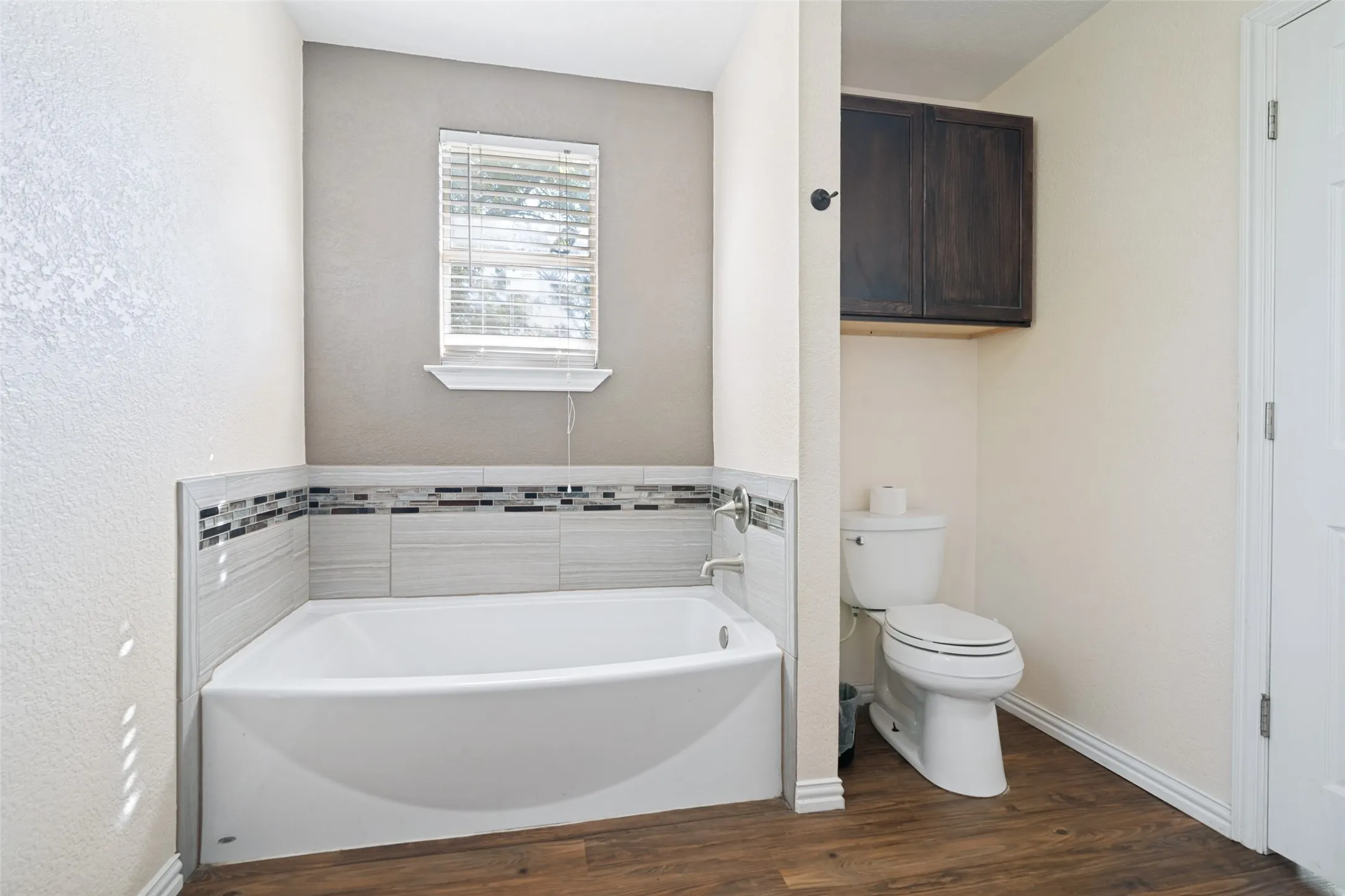 Soaking tub featuring a decorative tile surround and chrome fixtures