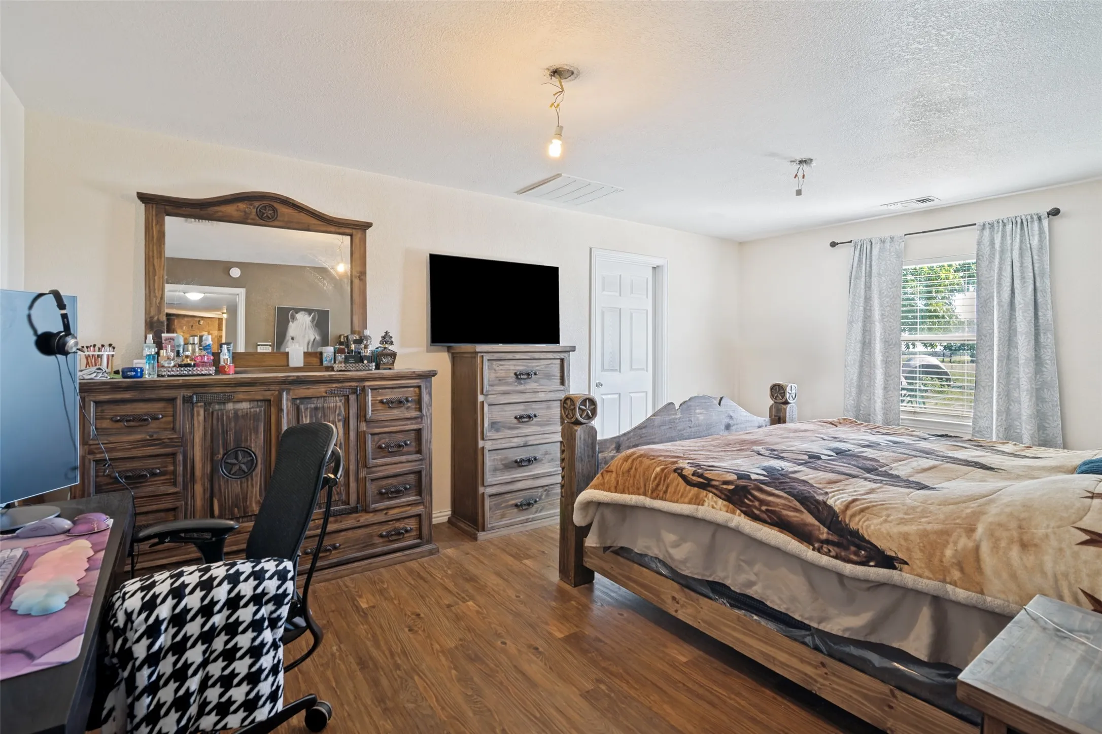 Room featuring wood-finish flooring, a window with blinds, and white walls