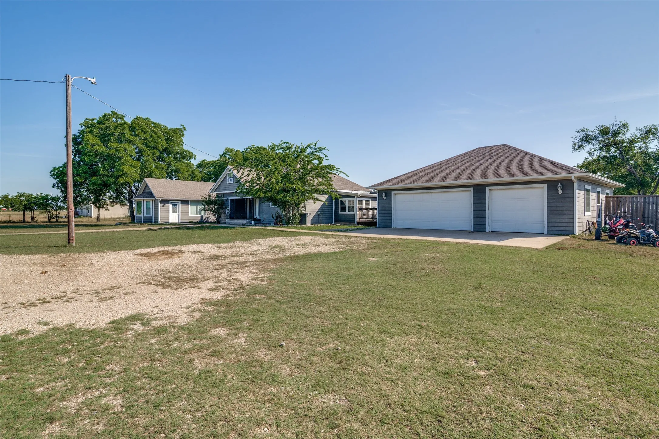 Detached garage with two white overhead doors and blue horizontal siding, situated on a grassy lot