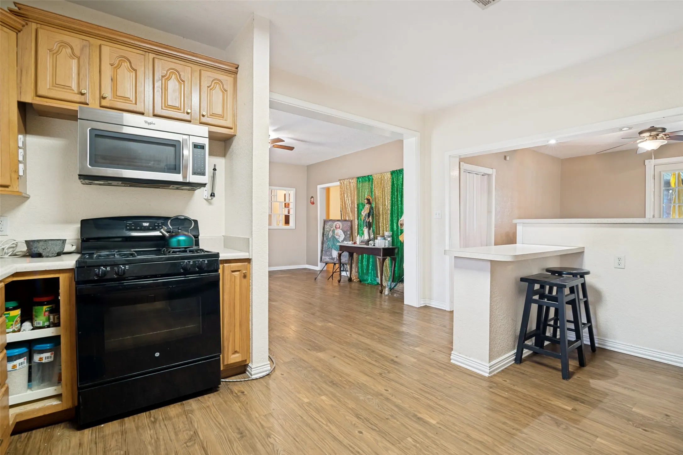 Kitchen with light wood-finish cabinetry, a black range, and a stainless steel microwave