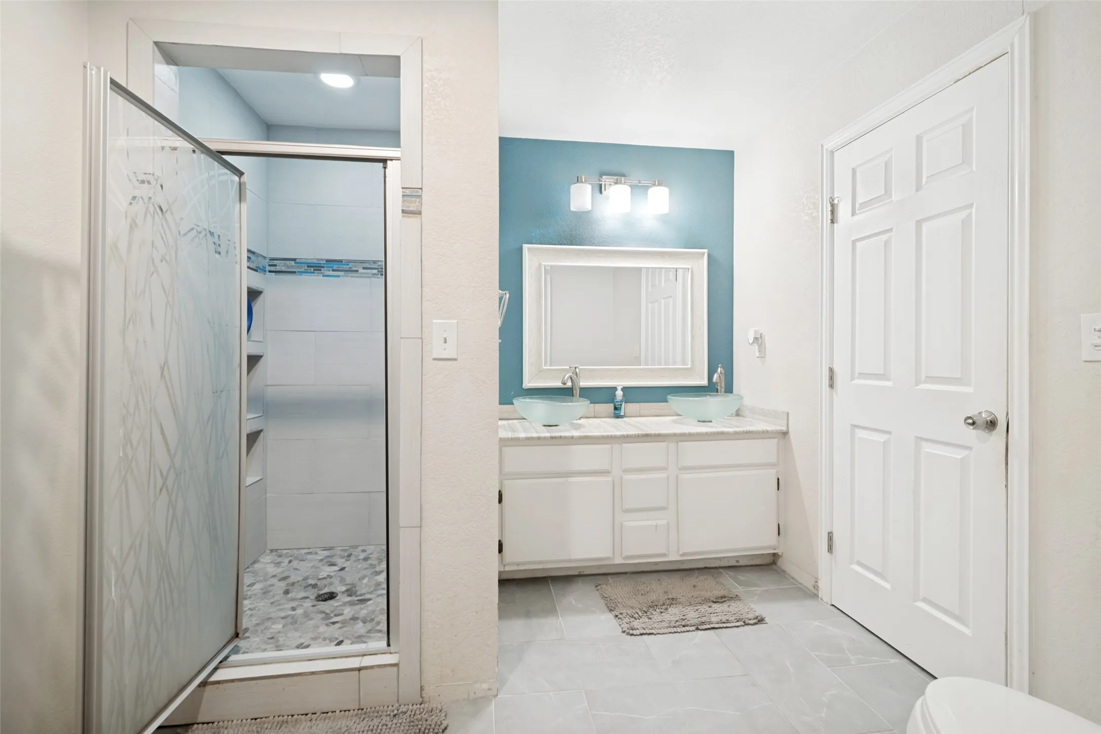 Bathroom featuring a walk-in shower with patterned glass enclosure, white tile surround, and mosaic accent band