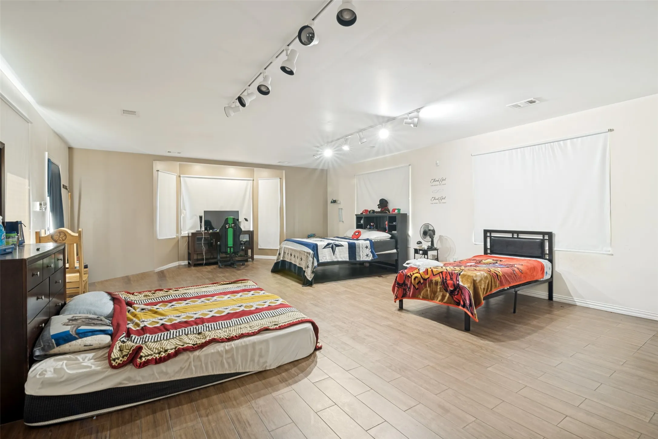 Spacious room featuring wood-finish flooring and track lighting