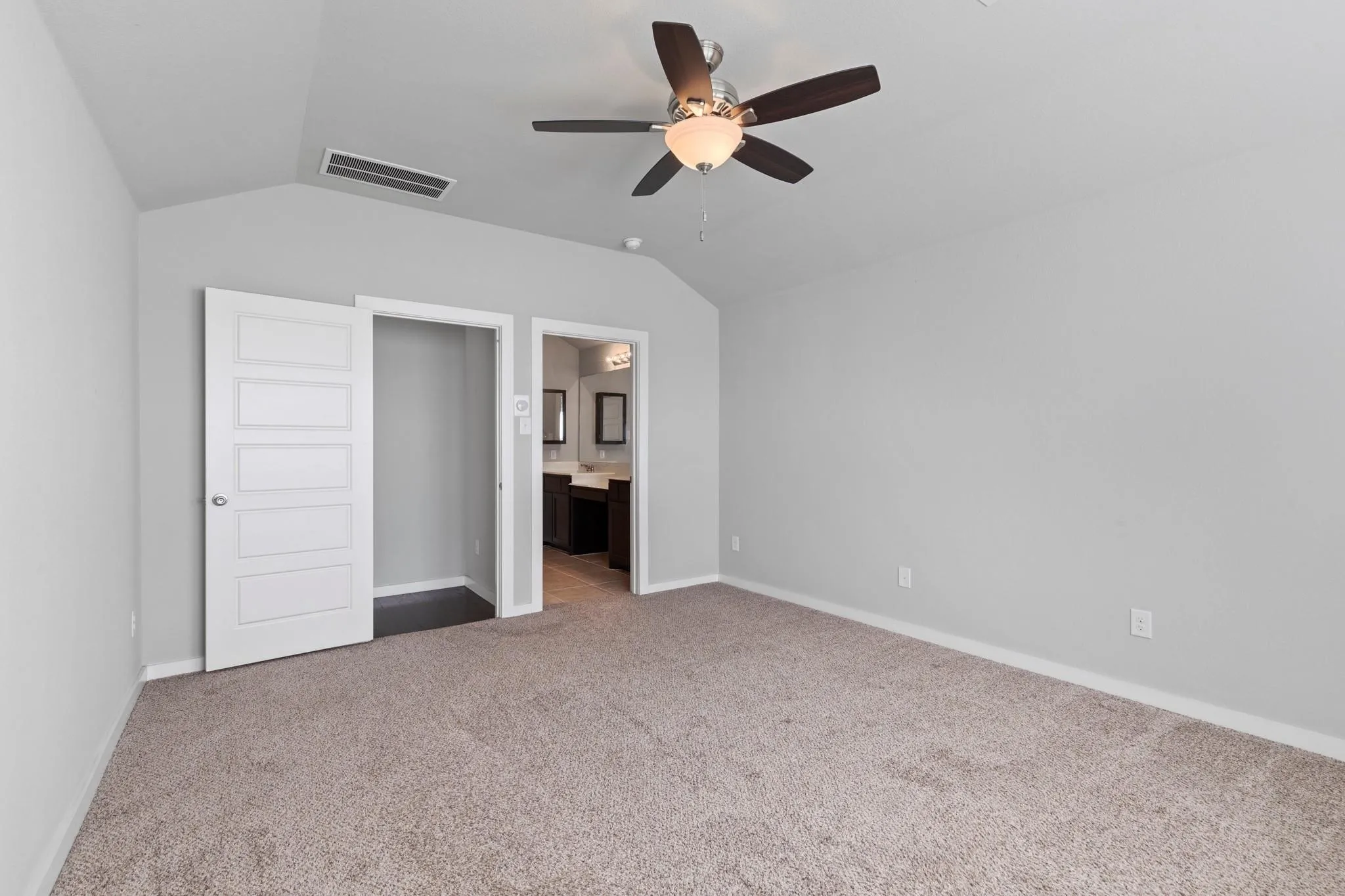 Carpeted room with a vaulted ceiling and a ceiling fan with light fixture