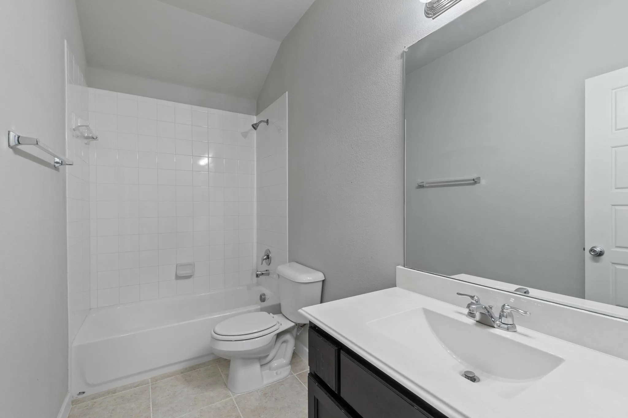 Bathroom with a single vanity featuring a white countertop and undermount sink, a large wall-mounted mirror, and a shower/tub combination with white subway tile surround