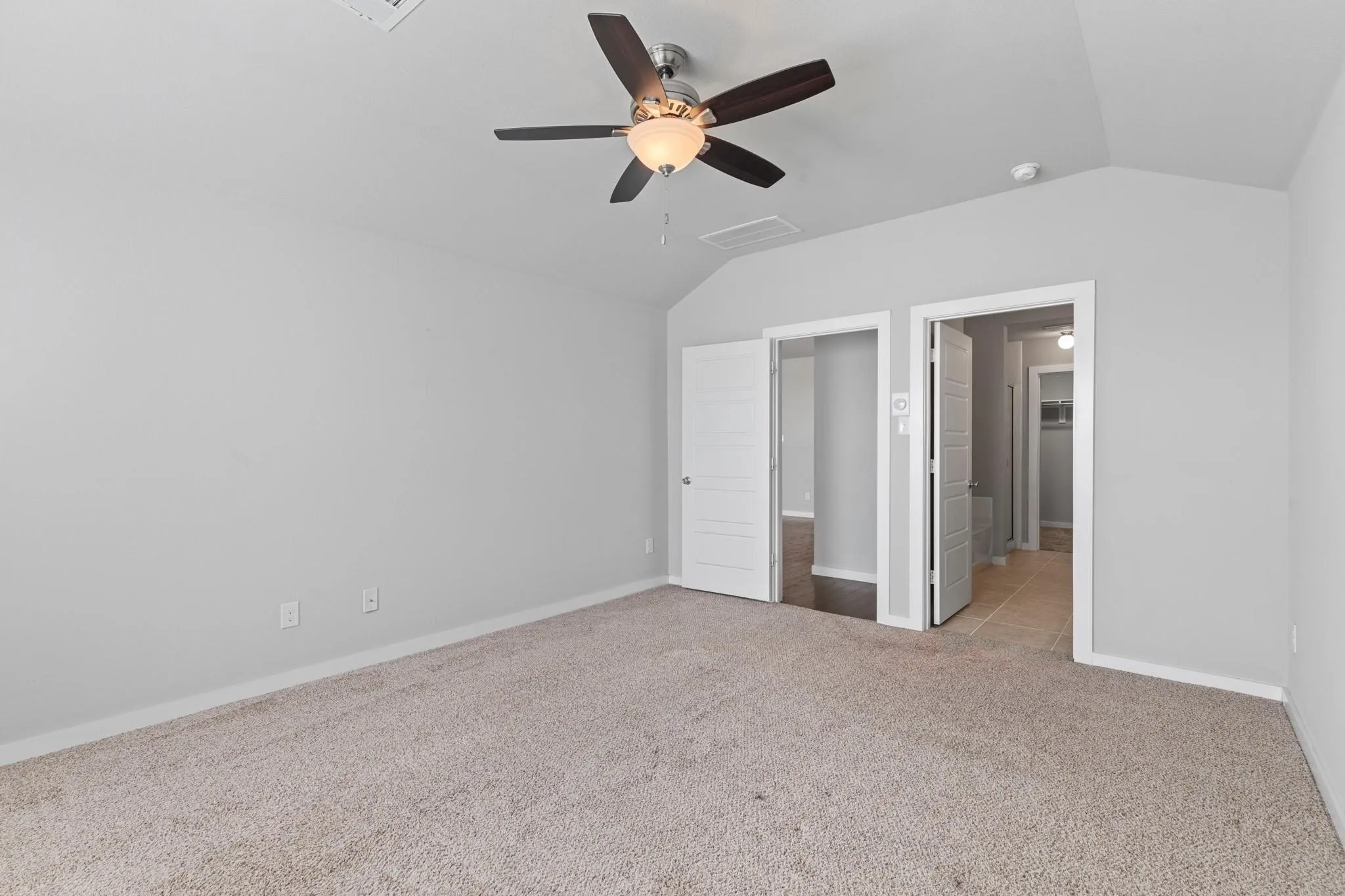Spacious room featuring vaulted ceilings, light gray wall paint, and beige carpeting