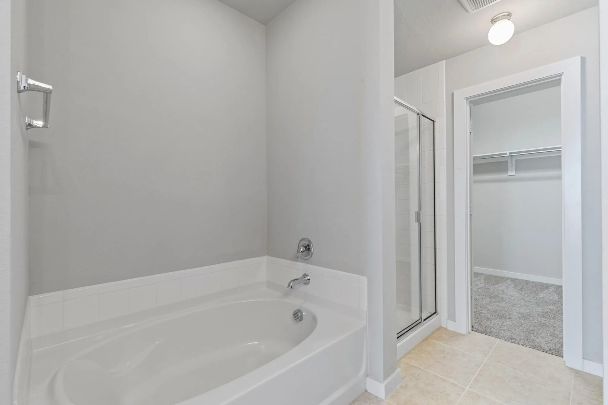 Bathroom featuring a built-in soaking tub with chrome fixtures, a clear glass shower enclosure, and neutral-toned wall paint