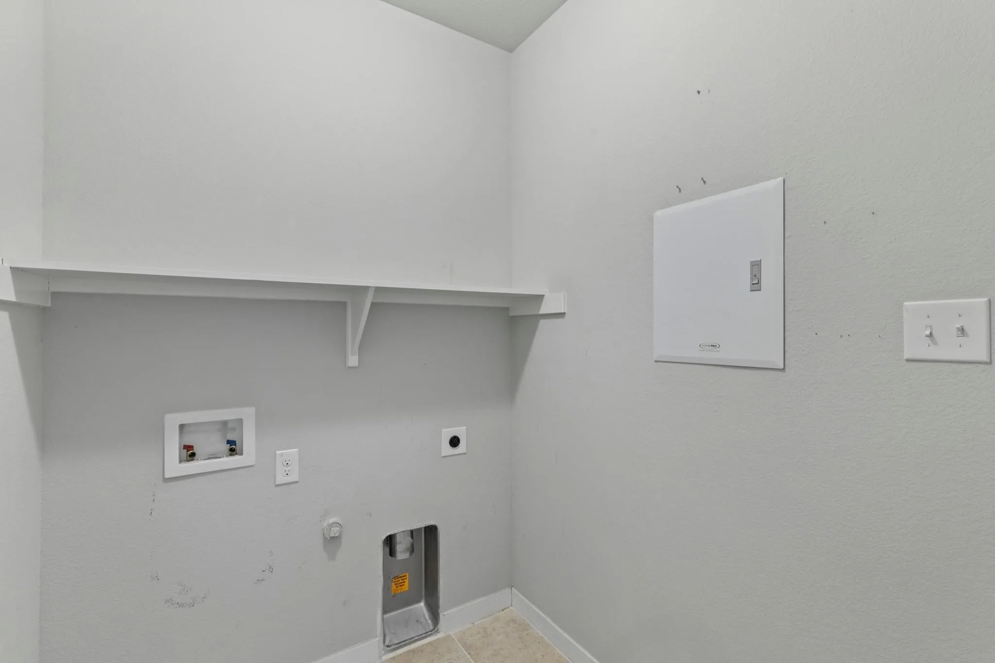 Utility room with a white wall shelf, appliance hookups, and tiled flooring