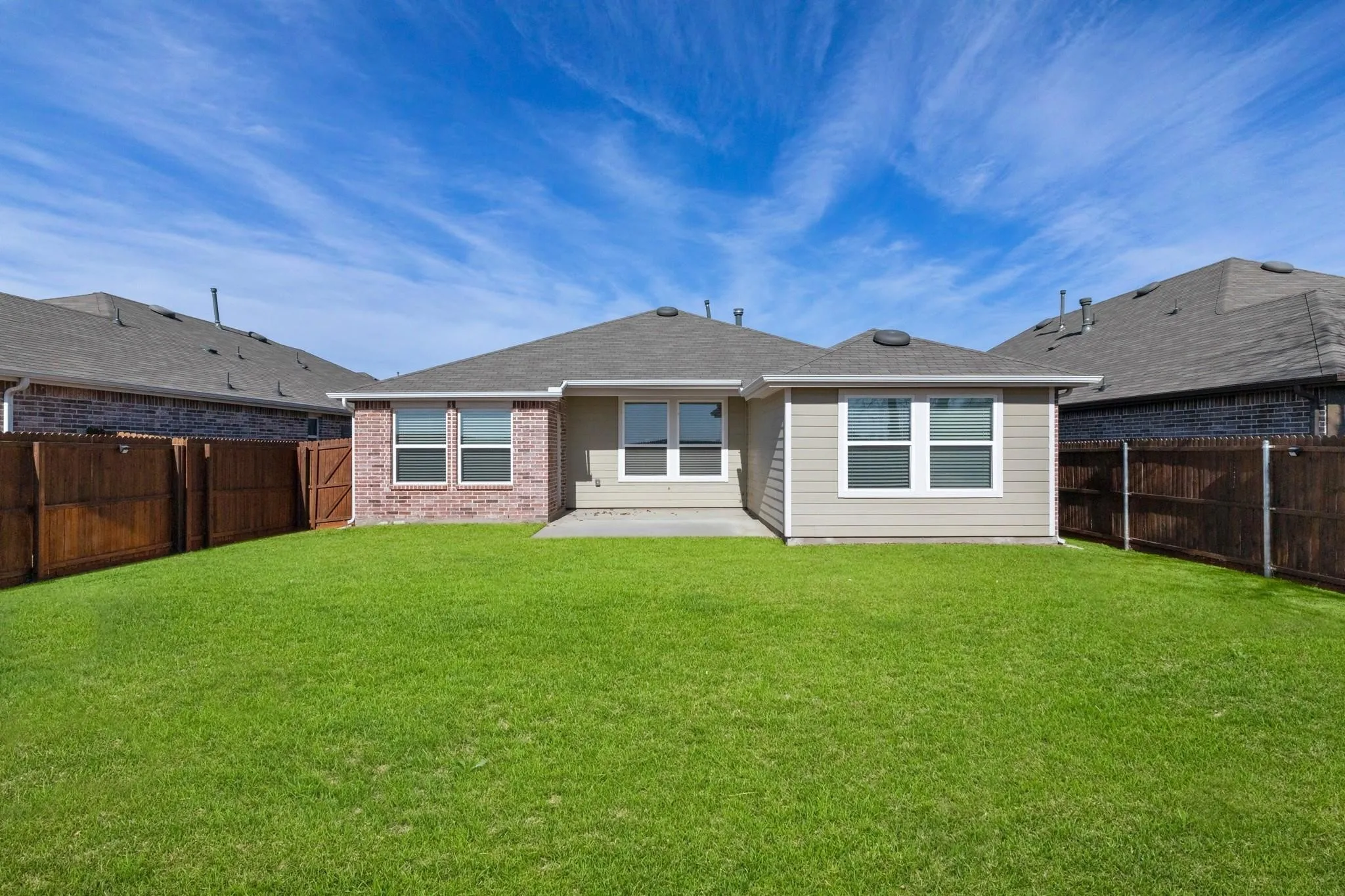 Expansive green lawn with a full wooden privacy fence