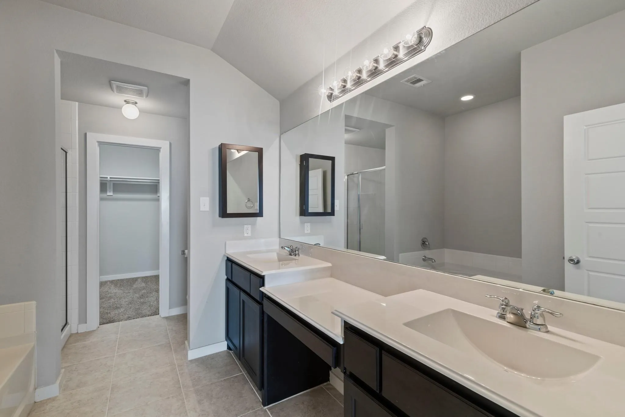 Bathroom featuring dual dark wood vanities with integrated sinks and light countertops