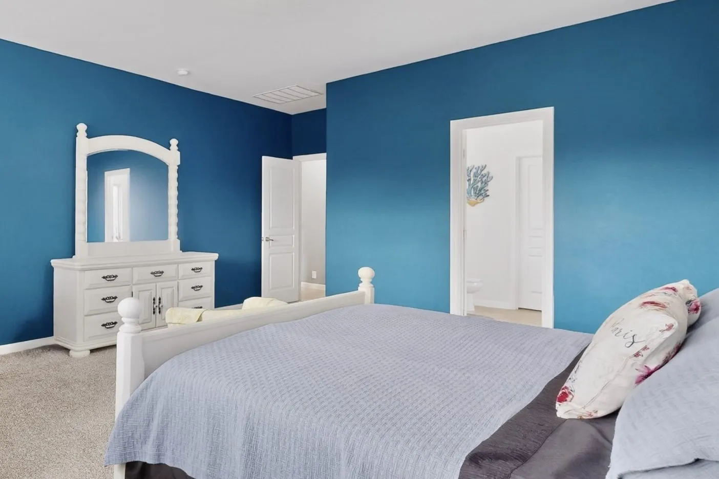 Carpeted bedroom with a bright blue accent wall and white trim
