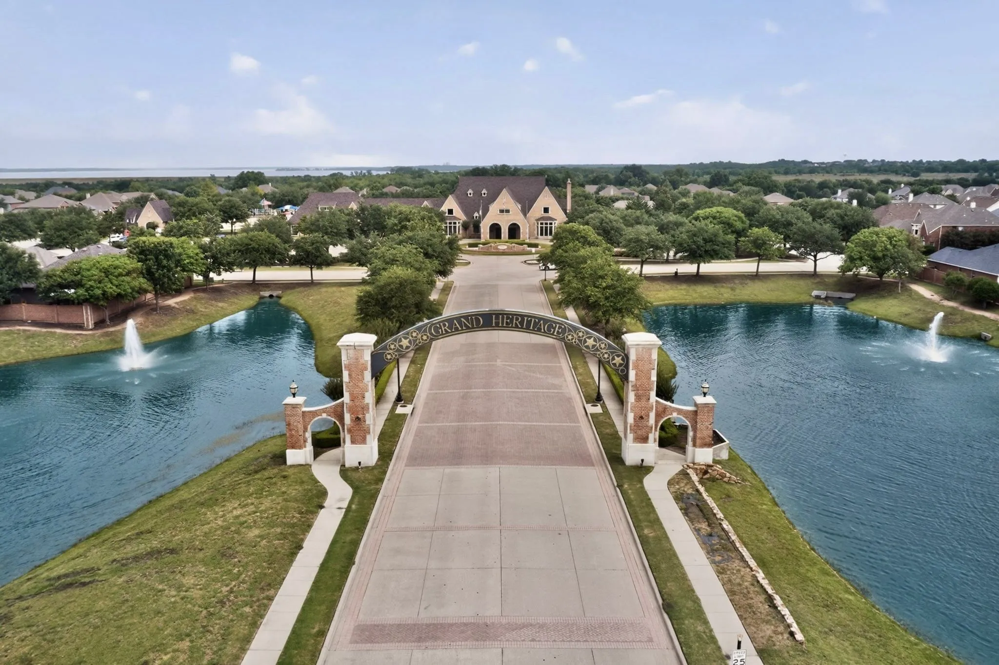 Grand entrance featuring a decorative archway, brick and stone pillars, and flanking waterways with fountains