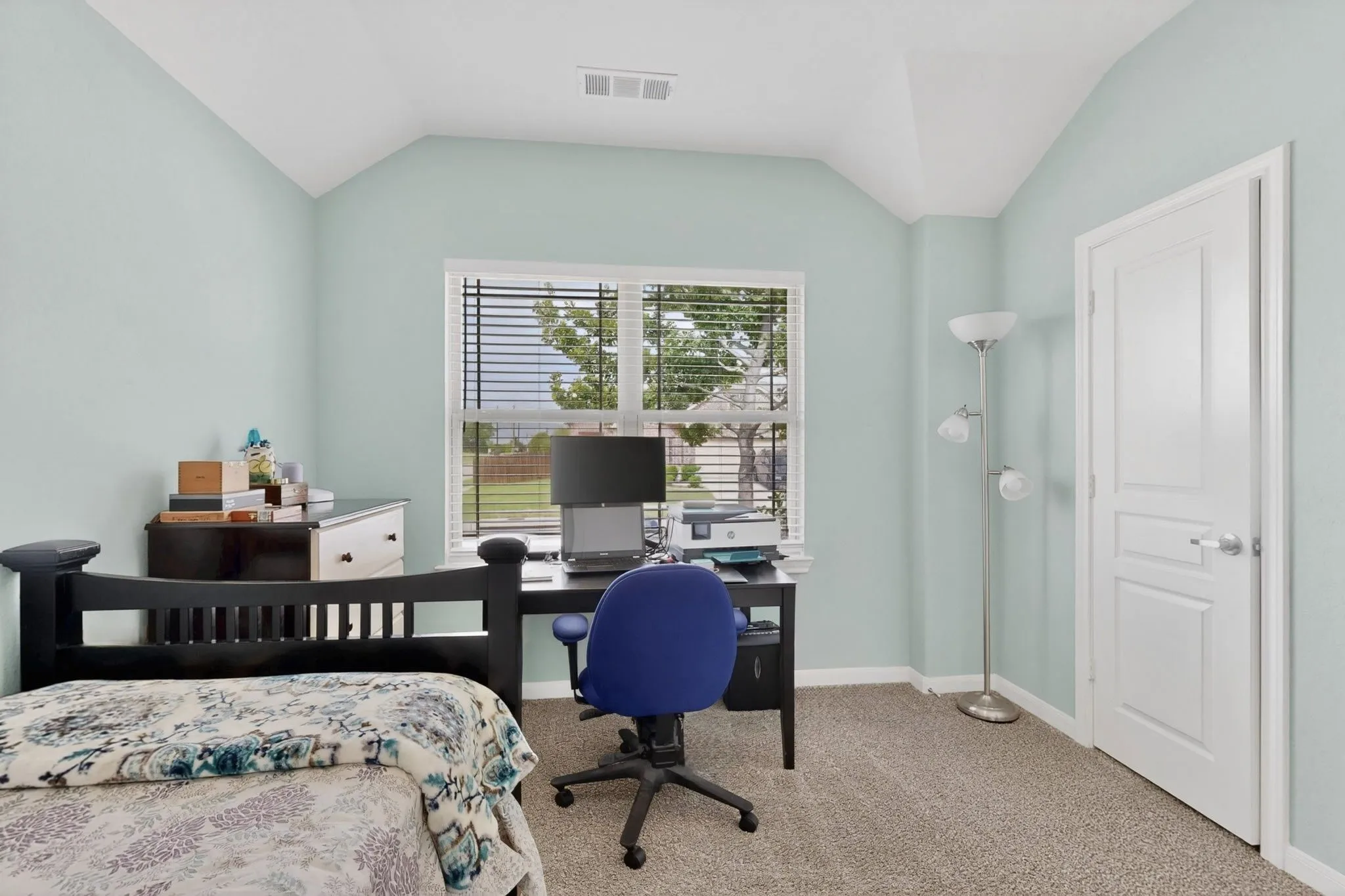 Carpeted room featuring a window with blinds, a vaulted ceiling, and a paneled interior door