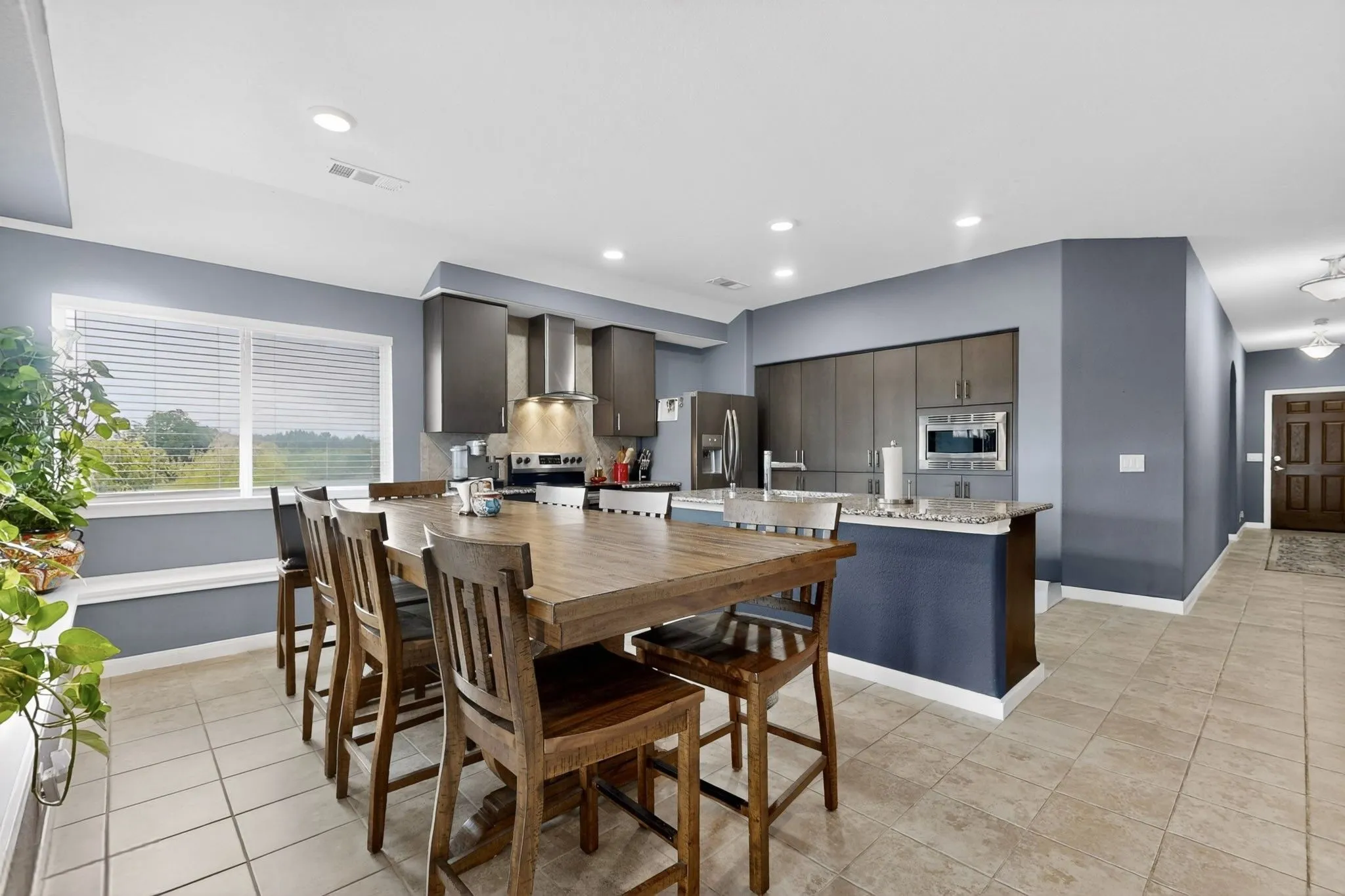Open-concept kitchen and dining area featuring a built-in oven, stainless steel refrigerator, and recessed lighting