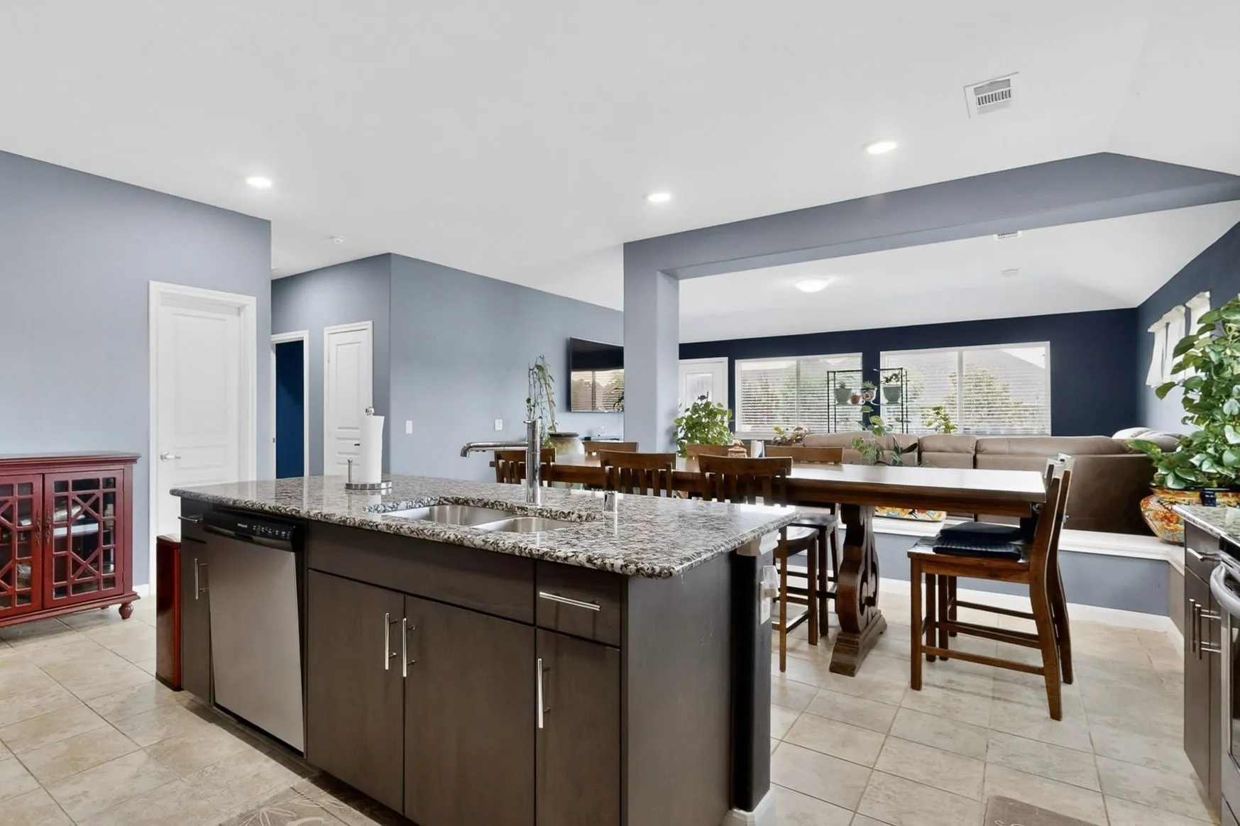 Kitchen island with granite countertop, stainless steel sink, and integrated dishwasher