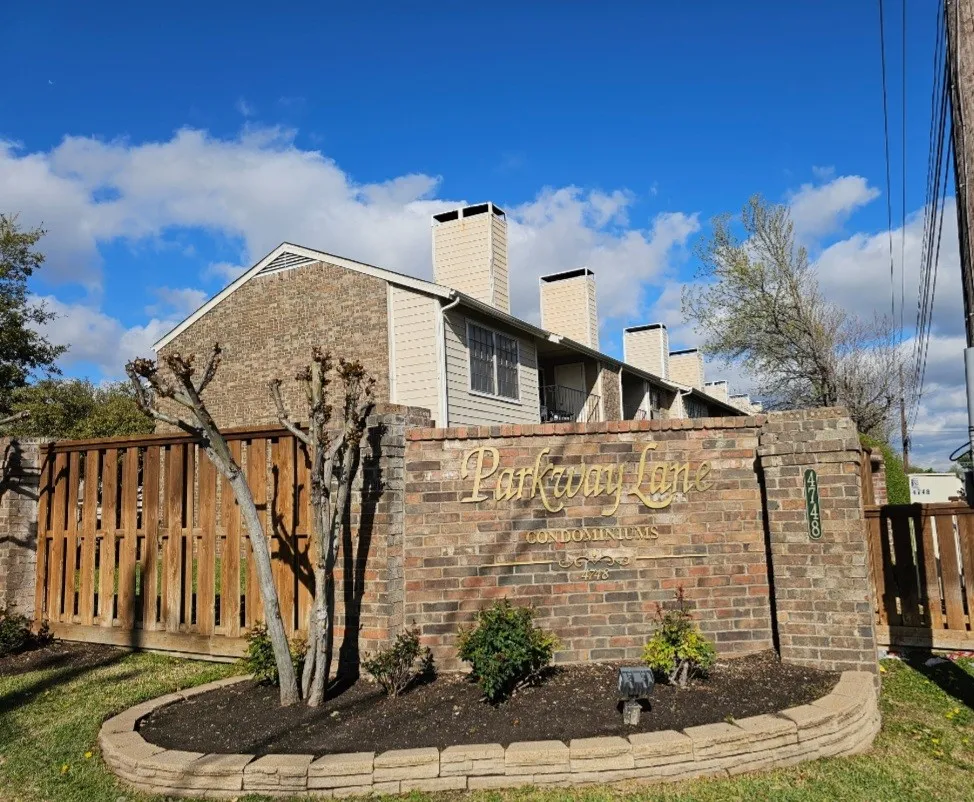 View of side of home with a chimney, fence, and brick siding