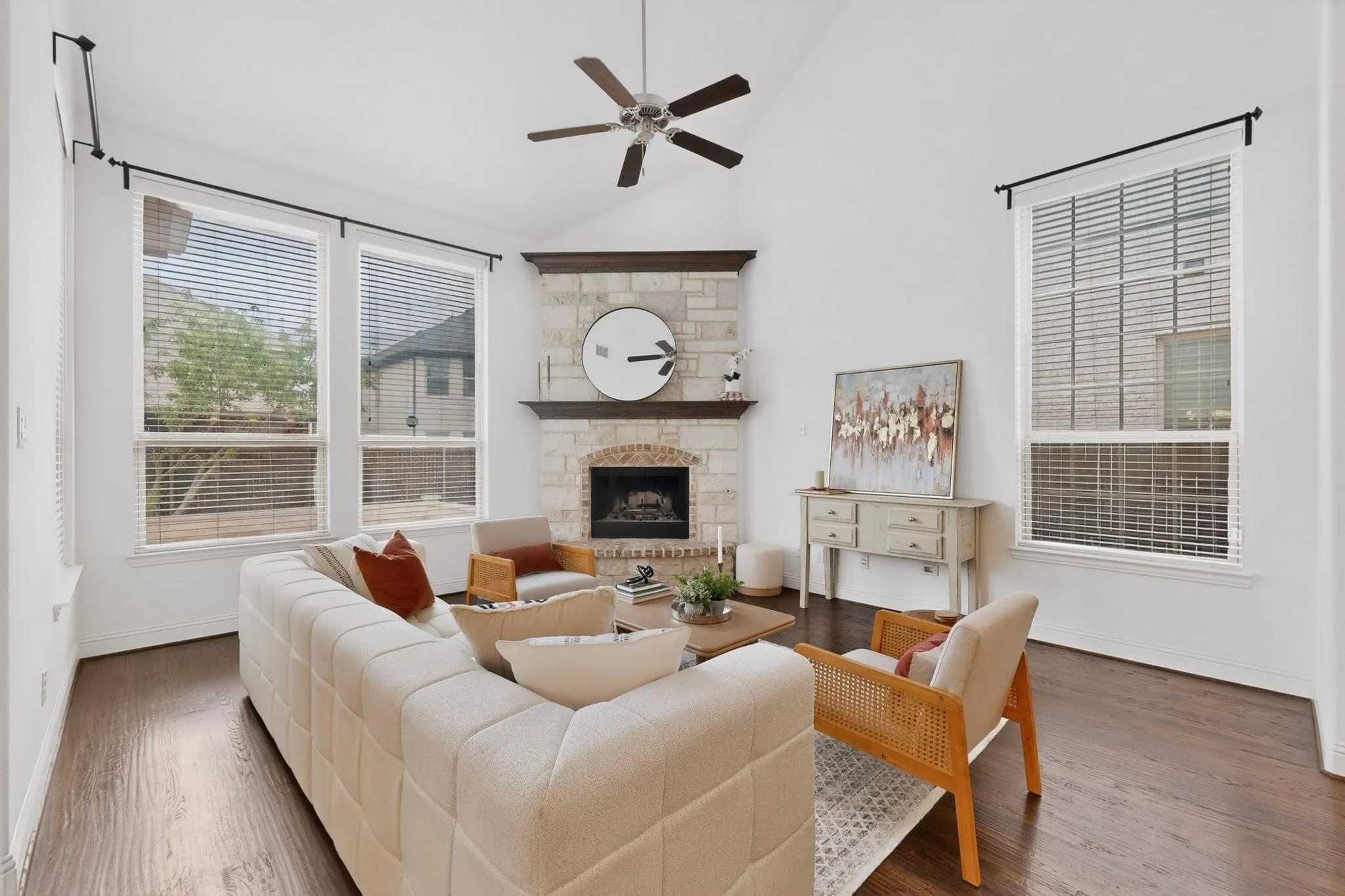 Bright living room showcasing a fireplace, tall windows, and a ceiling fan, creating a welcoming space.