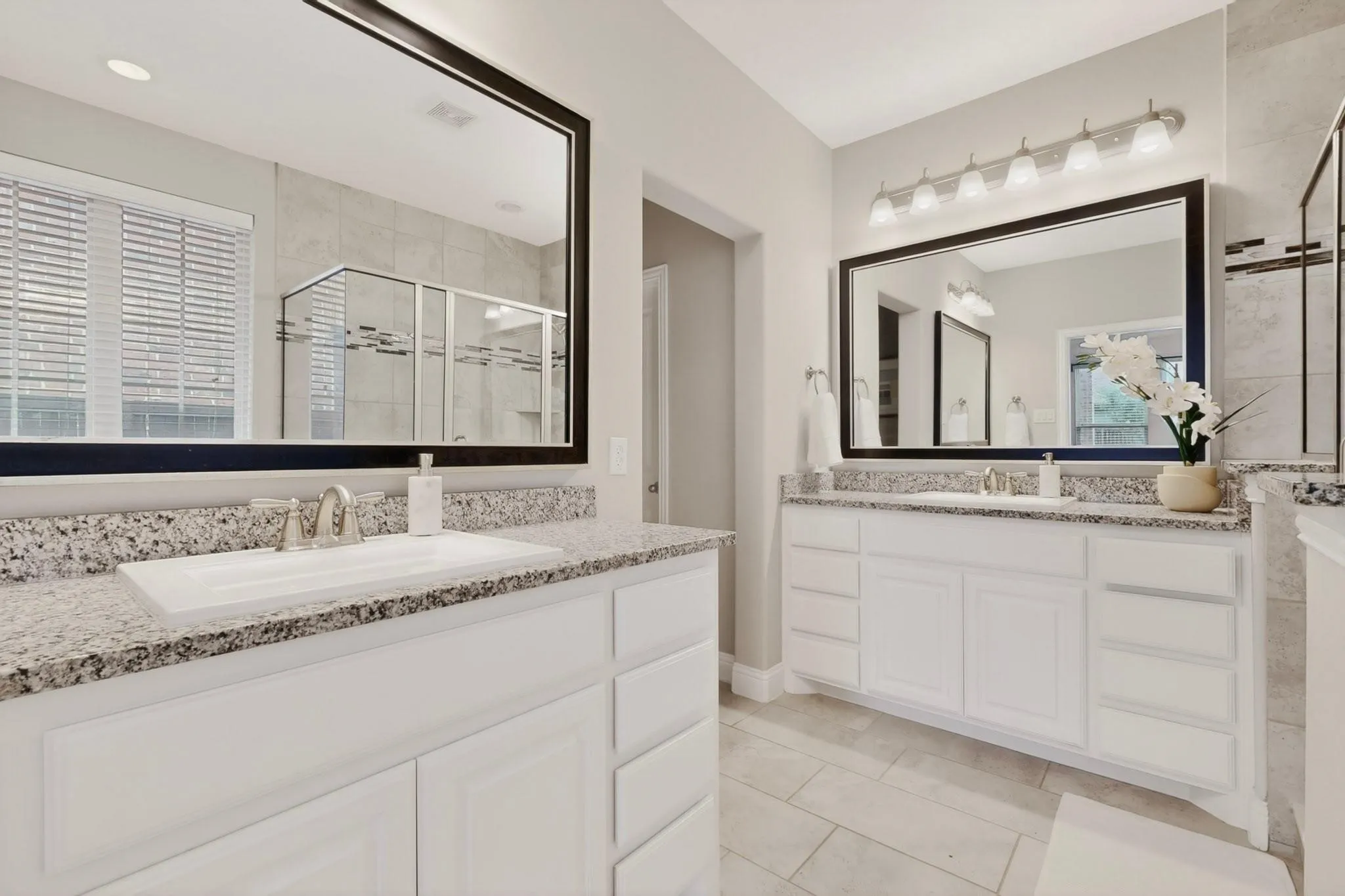 A bright primary bathroom featuring separate vanities and a large mirror for each, reflecting the space.