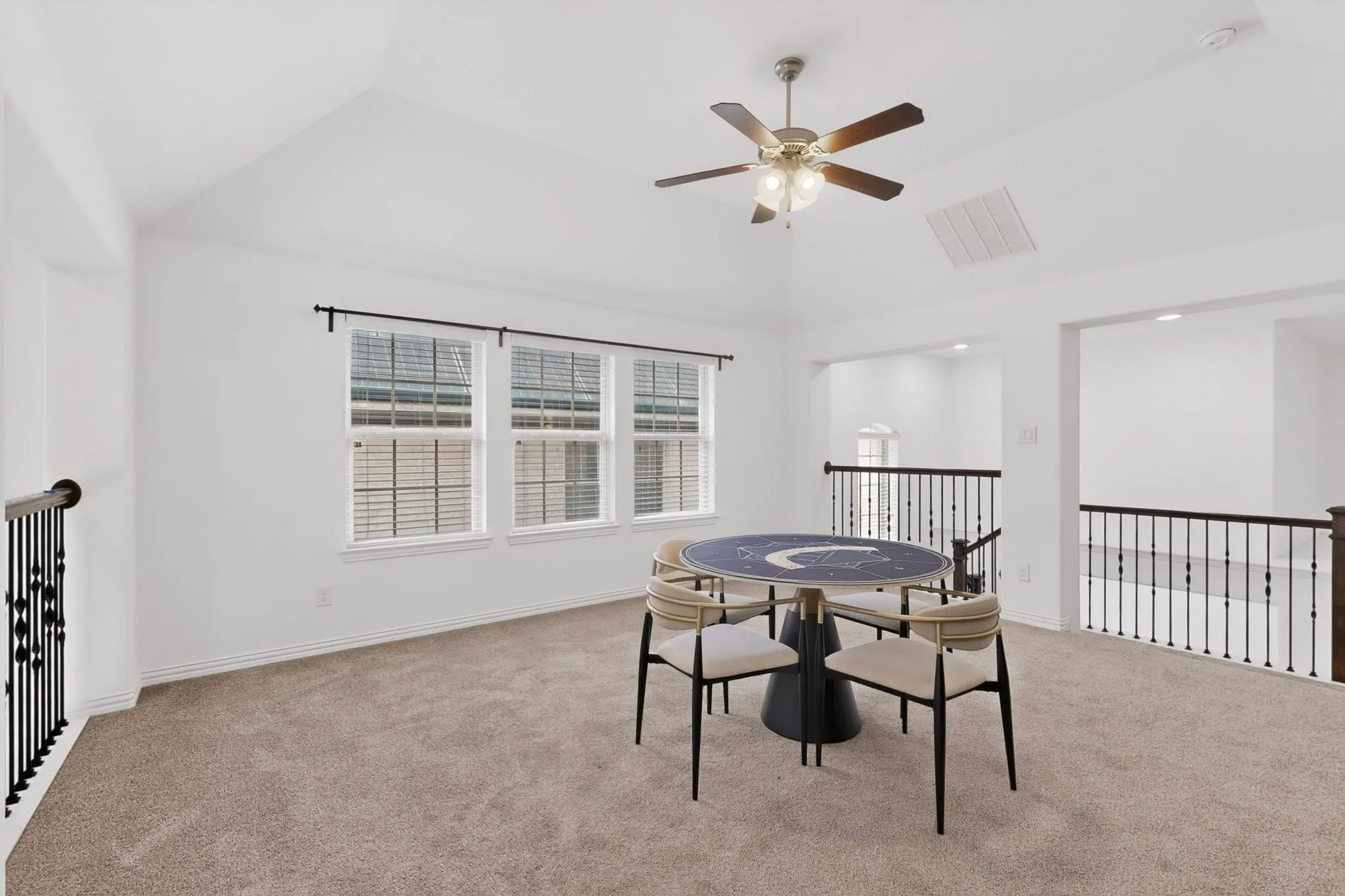 A spacious den featuring wide windows and a ceiling fan, creating a comfortable space.