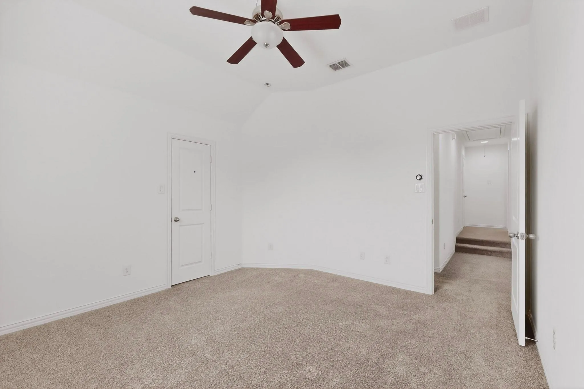 A bright bedroom featuring a ceiling fan and a walk-in closet