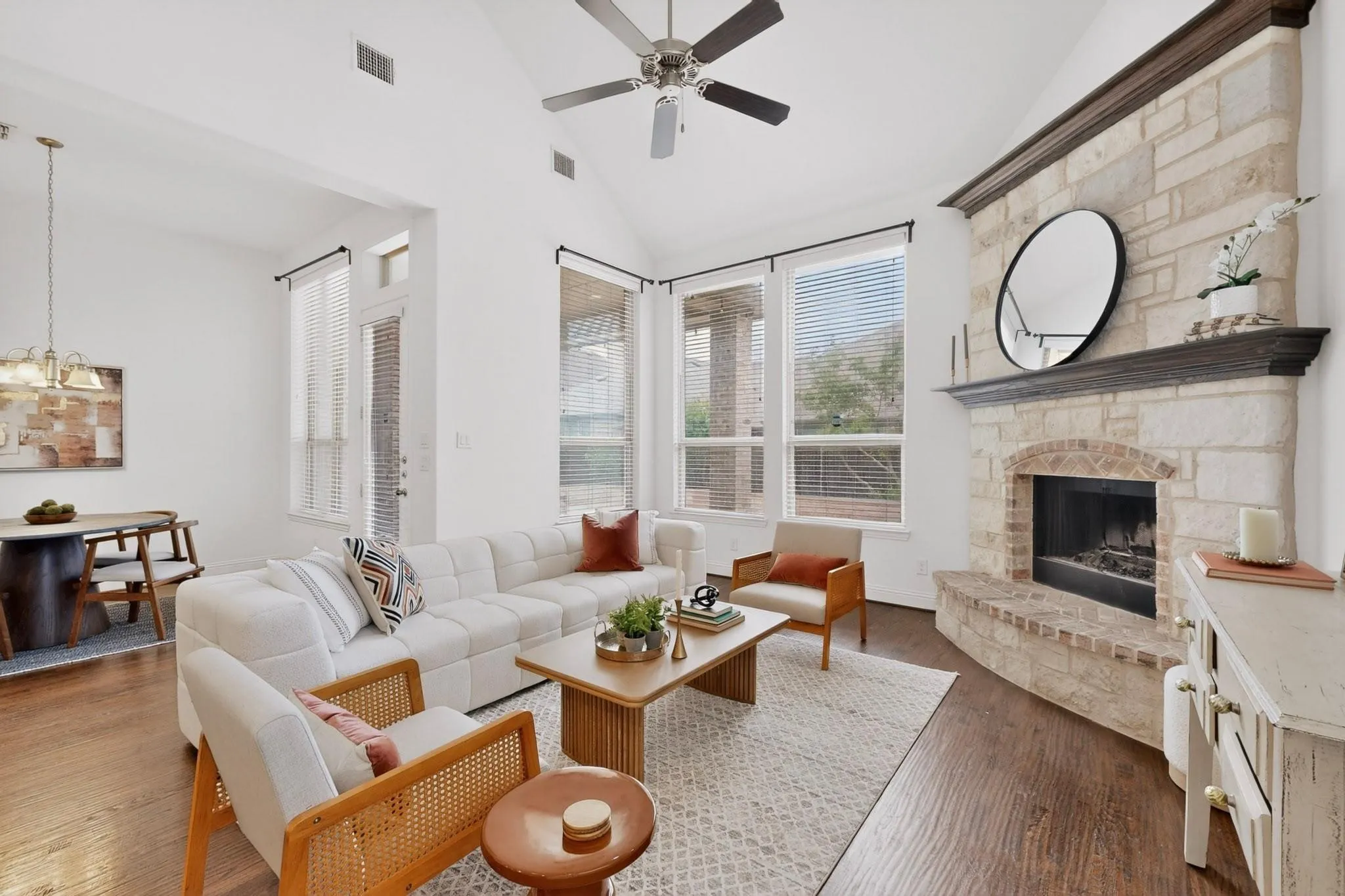 Bright living room showcasing a fireplace, tall windows, and a ceiling fan, creating a welcoming space.