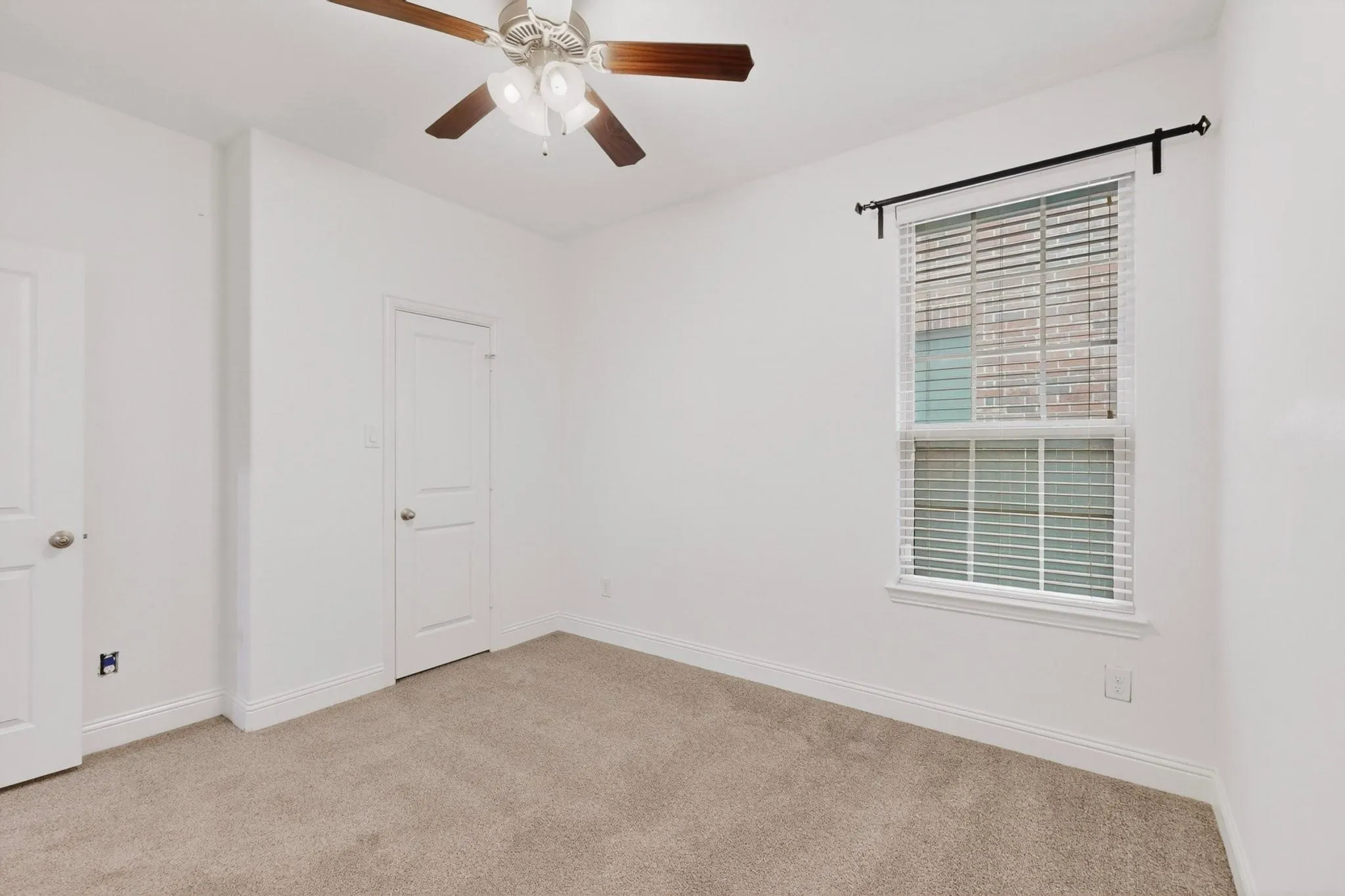 A bright bedroom featuring a ceiling fan, a window, and a walk-in closet