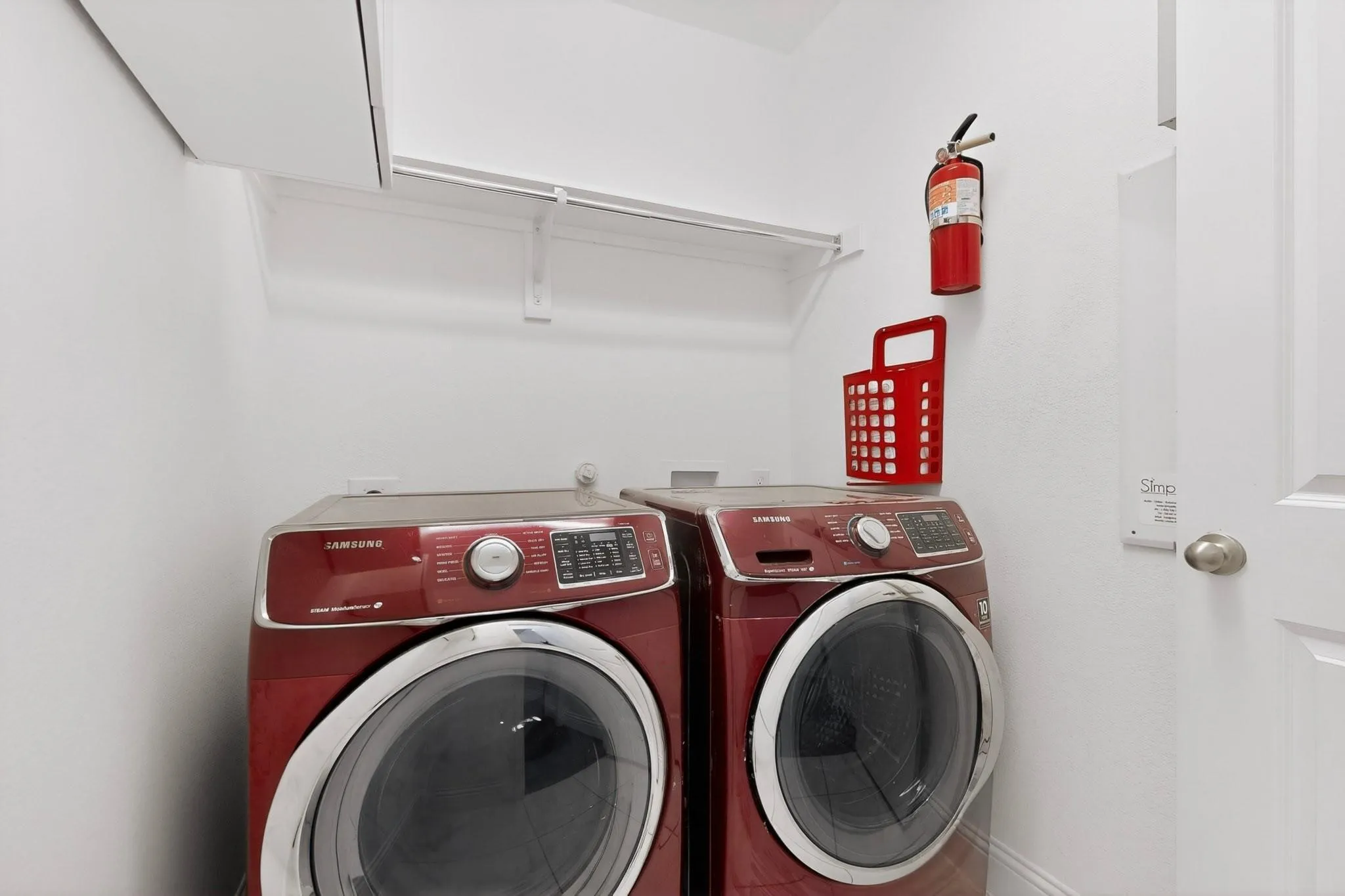 A compact utility room showcasing a side-by-side washer and dryer, with shelves above.