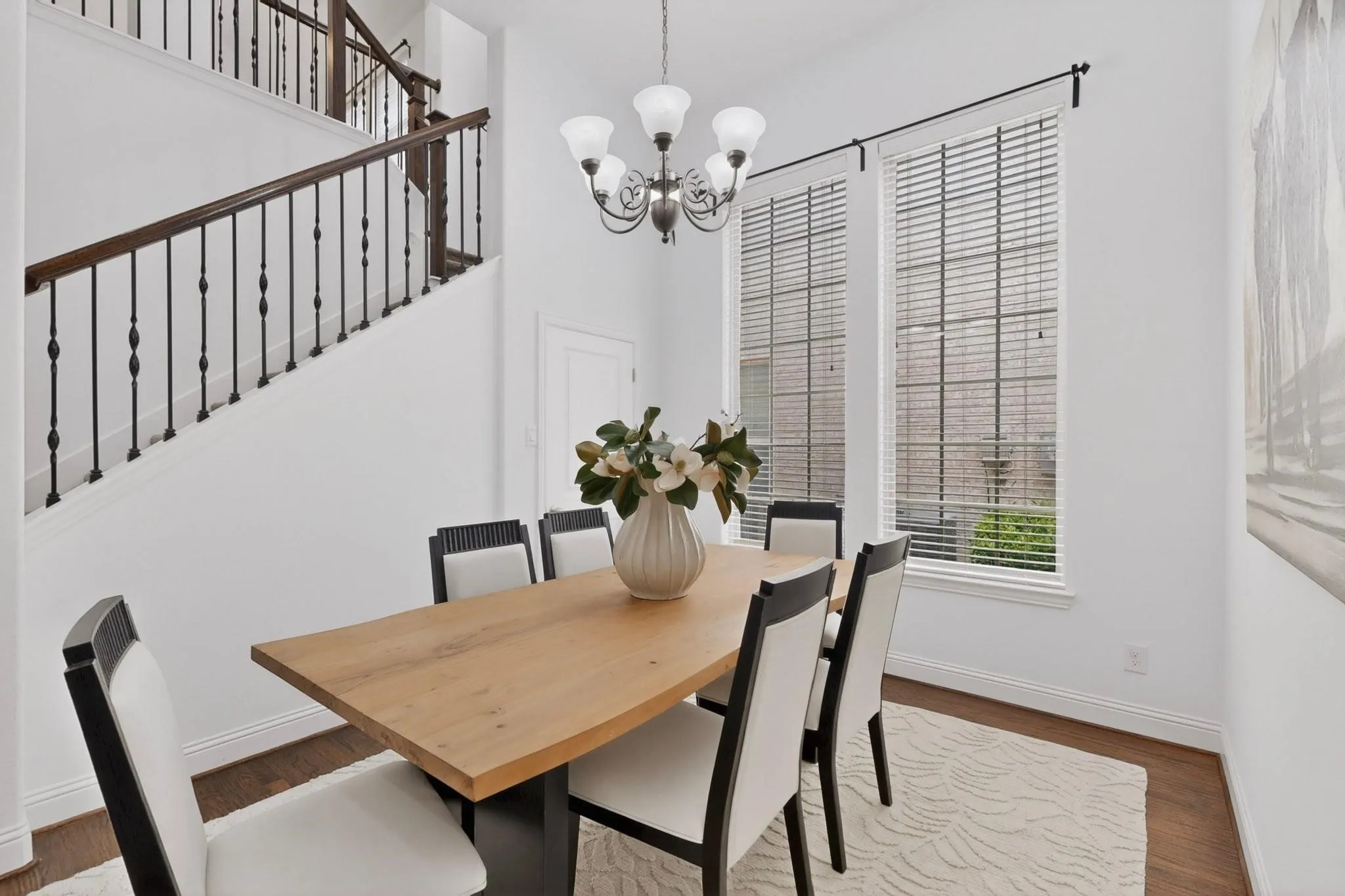 A charming dining area showcasing tall windows and a chandelier, perfect for dining and socializing.