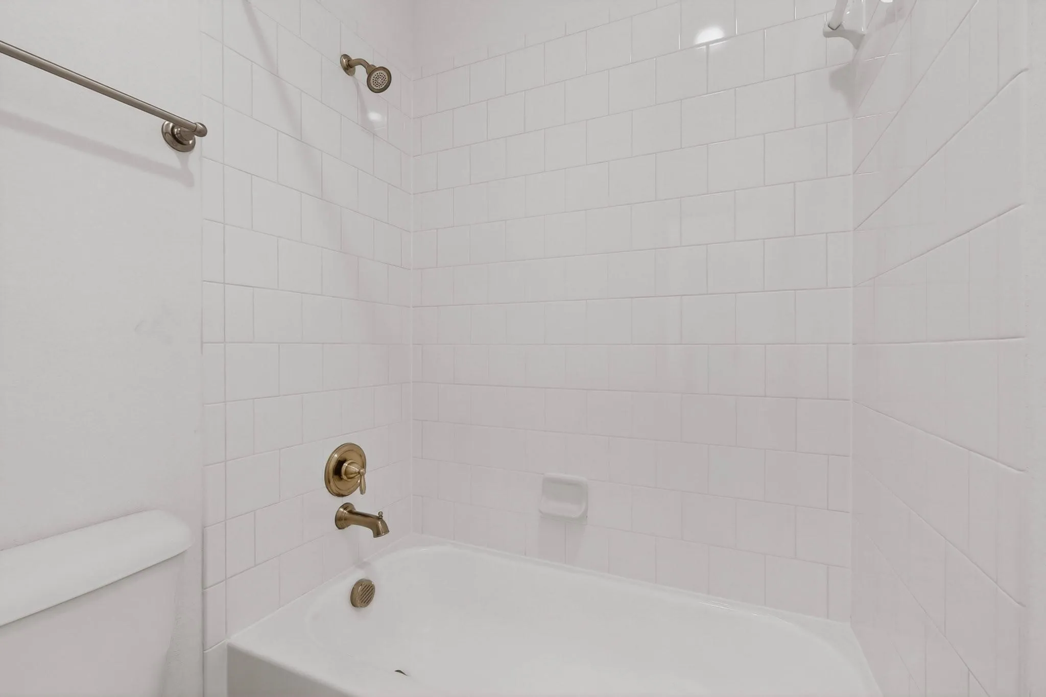 A bright white bathroom featuring a bathtub, toilet, and shower