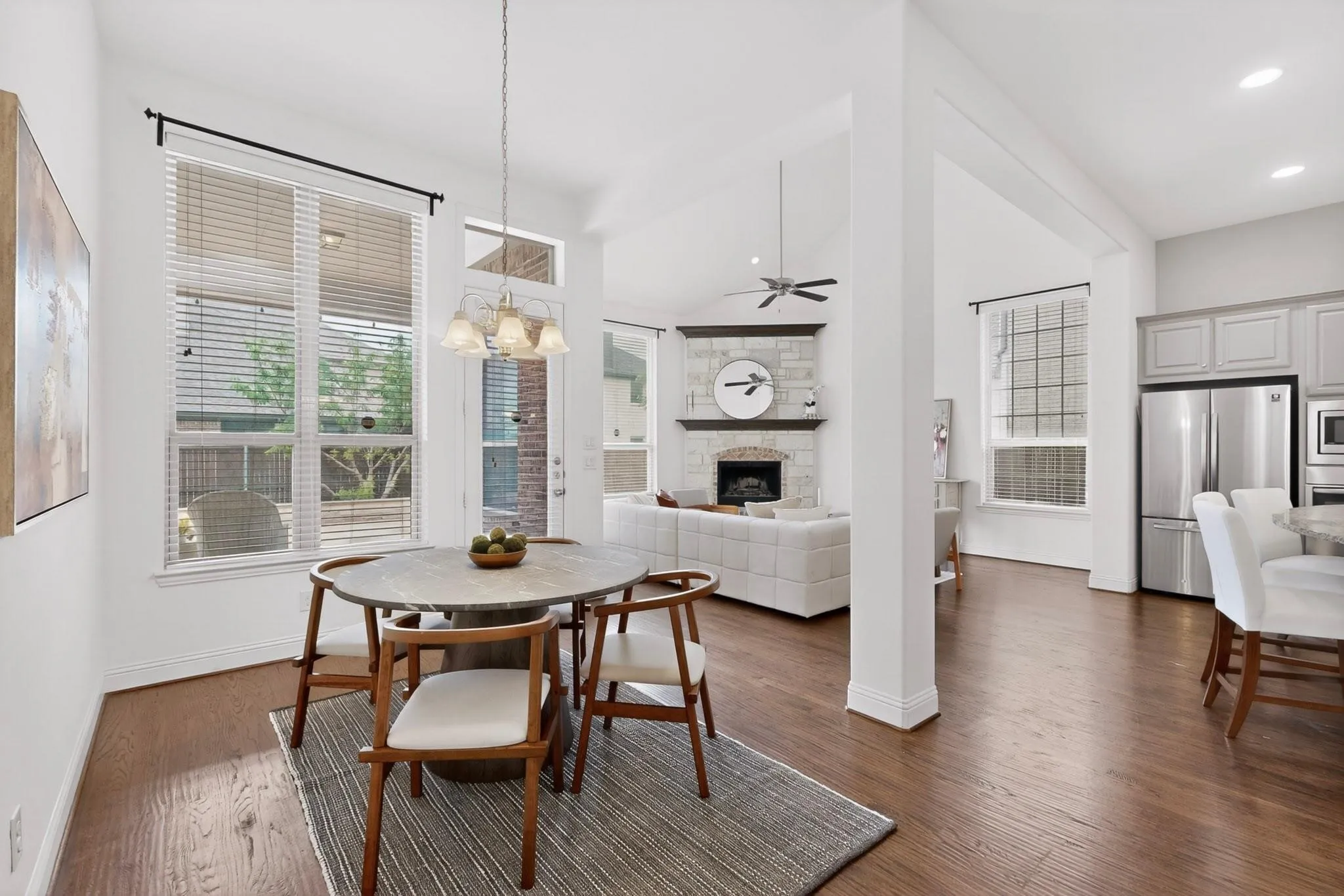 Spacious dining area showcasing elegant hardwood floors, tall windows and a chandelier, blending style and comfort for everyday living.