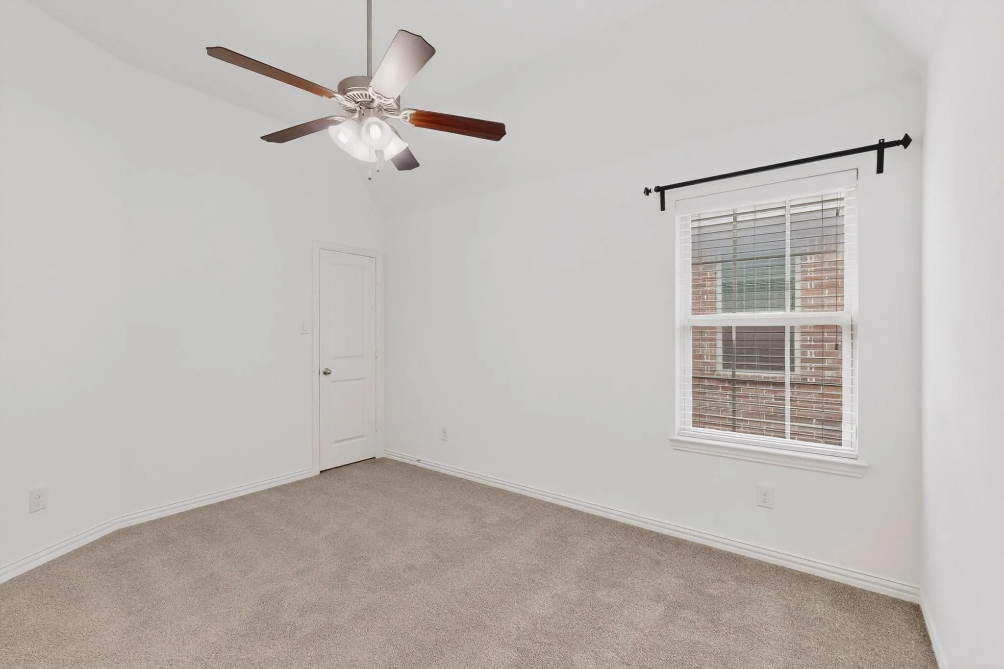 A bright bedroom featuring a ceiling fan, a window, and a walk-in closet