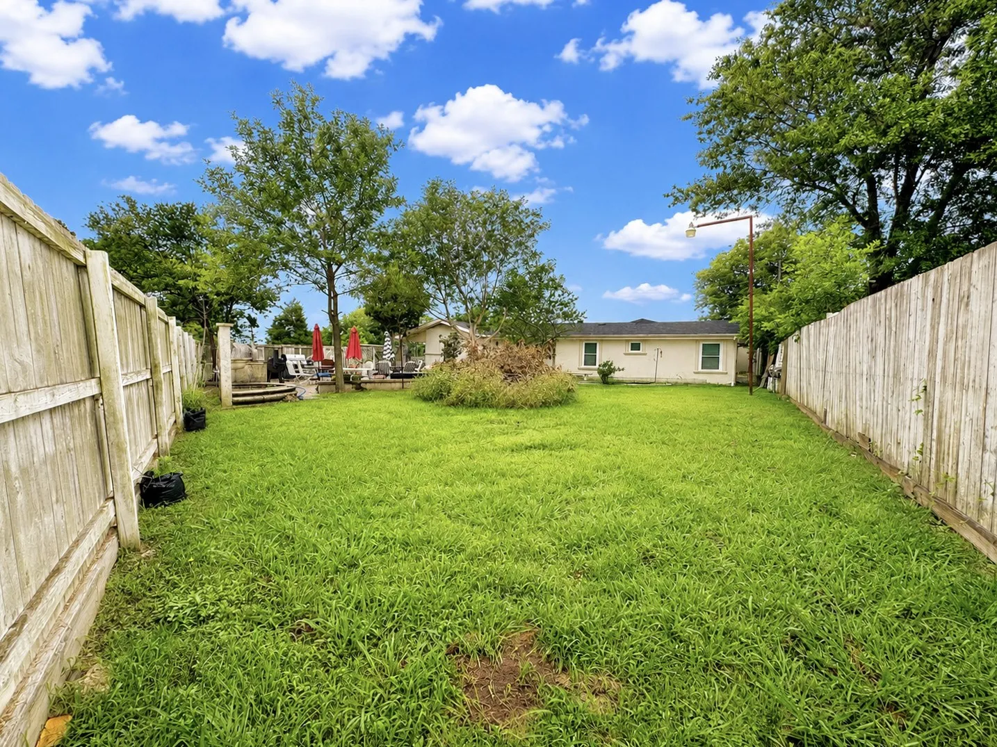 Expansive backyard featuring a large grassy area, privacy fencing, and mature trees