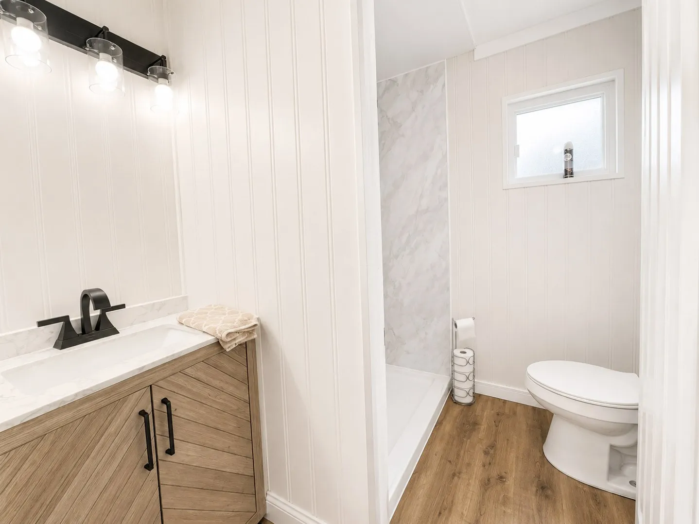 Hall Bathroom with wood-finish flooring and vertical paneling
