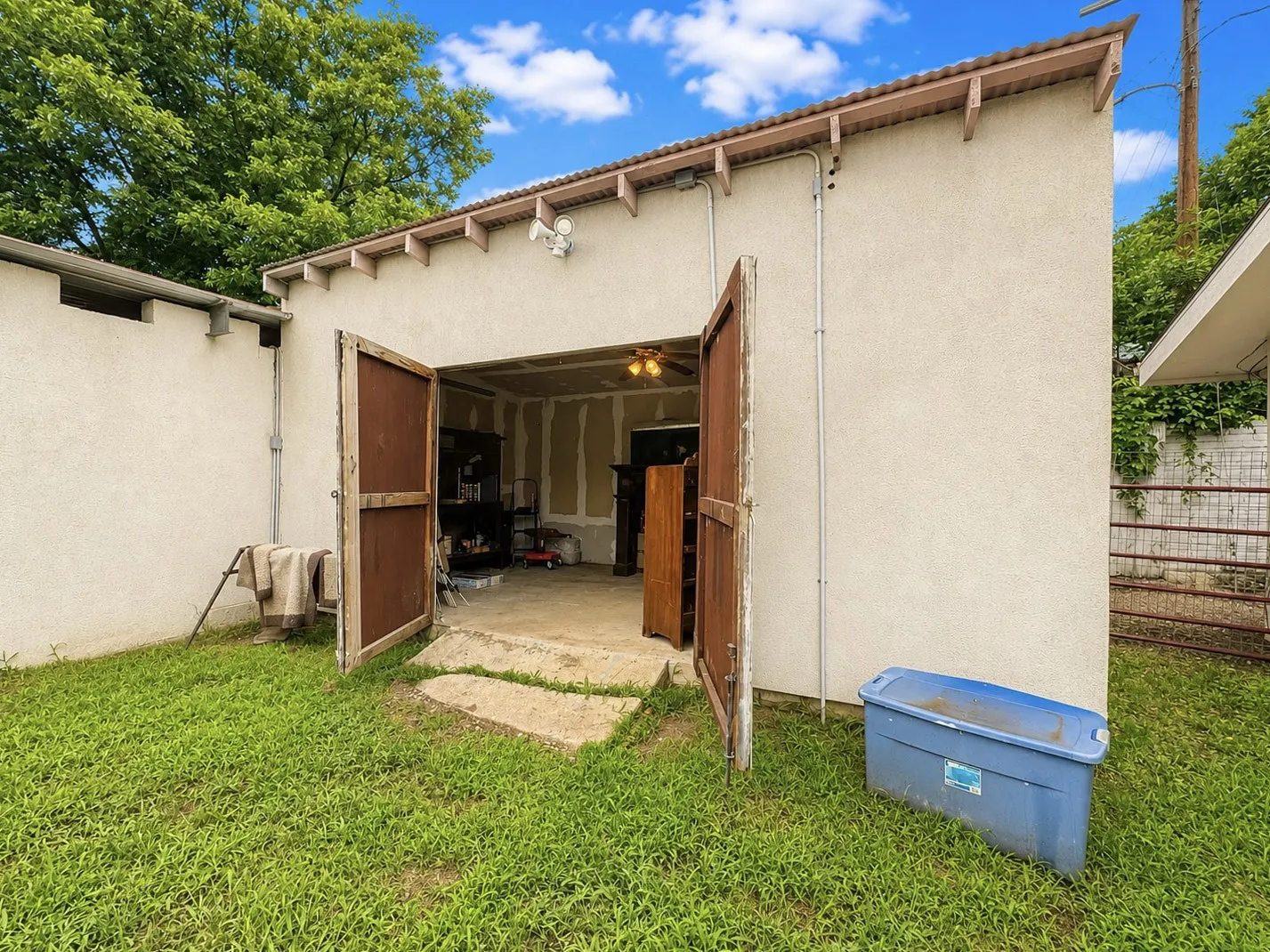 workshop with electricity~ Detached structure with a stucco exterior, corrugated metal roof, and double wooden doors