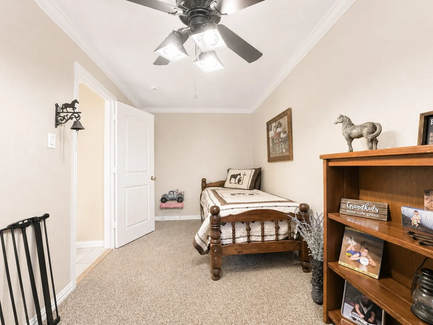 2nd bedroom. Carpeted room featuring crown molding, a ceiling fan with integrated lighting, a built-in wooden bookshelf, and a white paneled door