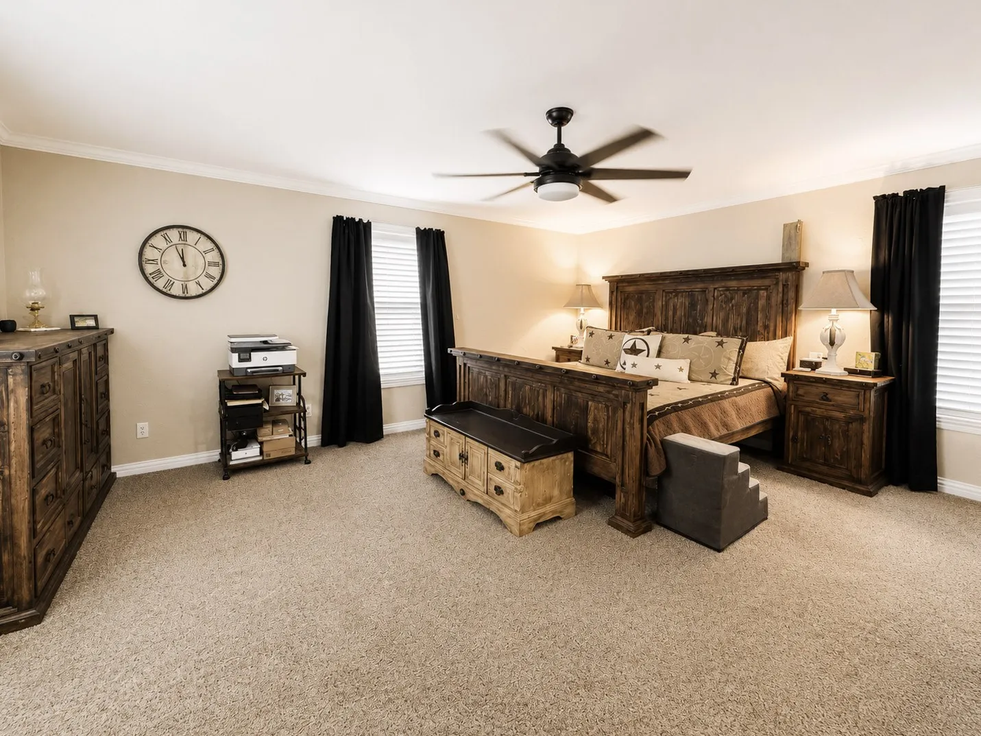 Spacious bedroom featuring light neutral wall tones, crown molding, and a ceiling fan with integrated lighting