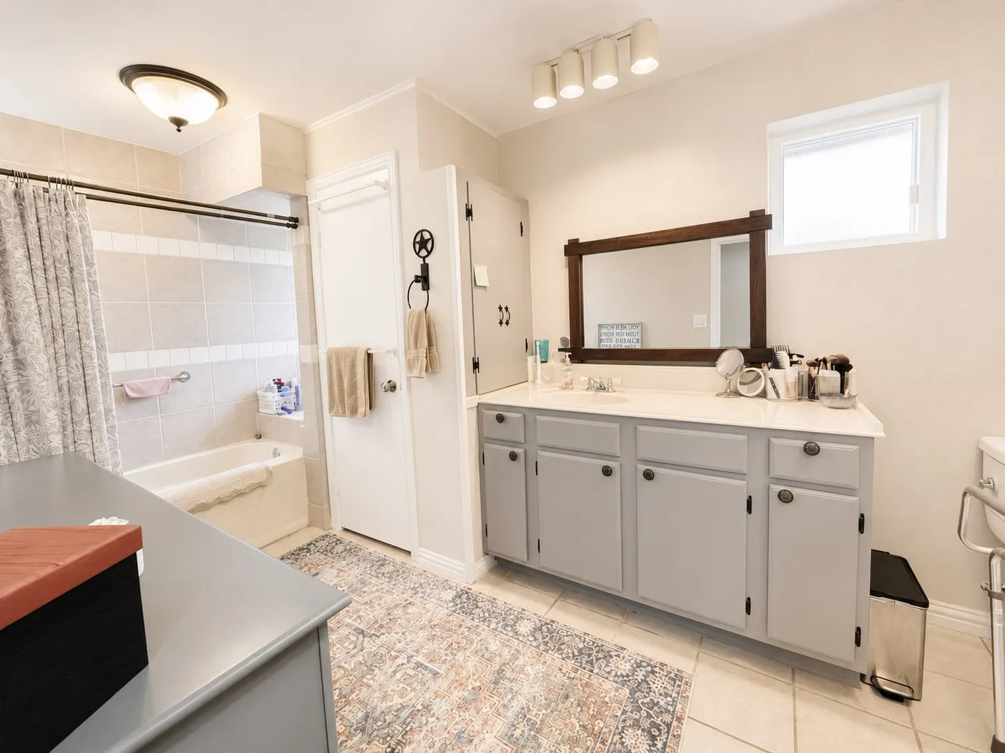 2nd Hall Bathroom featuring a tile-surround tub, a single vanity with painted cabinetry, and a framed mirror