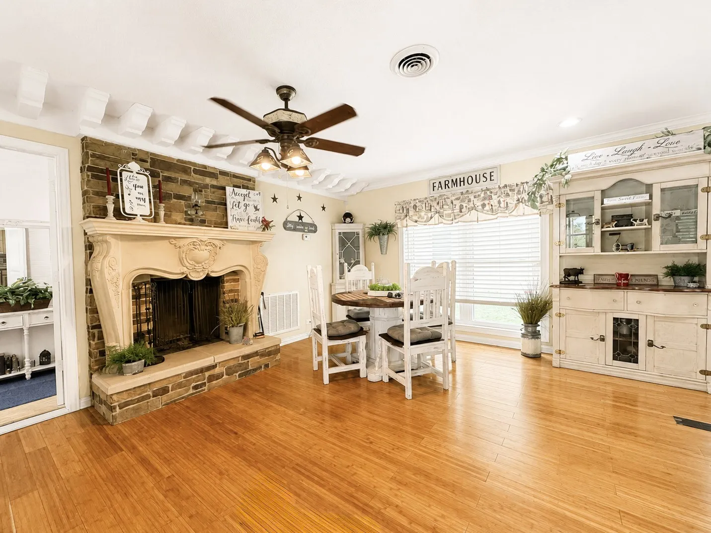 Hardwood flooring throughout a room featuring a stone-clad fireplace with a decorative mantel and hearth