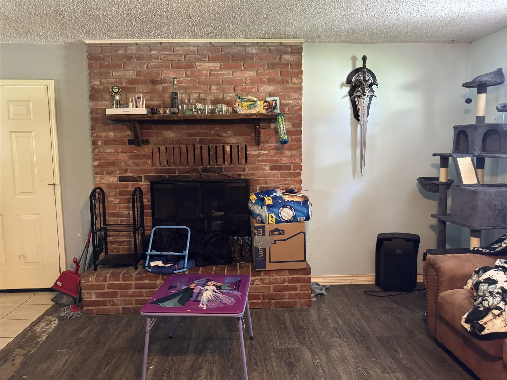 Brick fireplace with a black metal screen and a wood mantel shelf