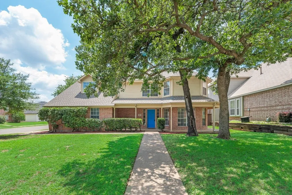 Two-story residence featuring a brick and siding exterior, a covered porch, and a bright blue front door