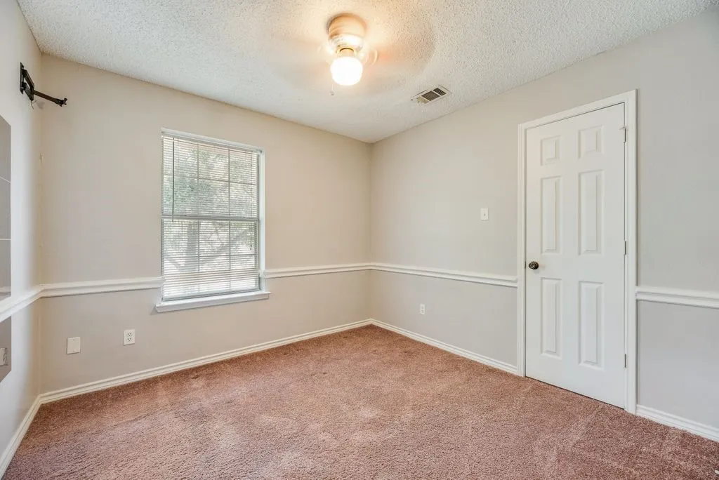 Room featuring light-colored walls with chair rail molding, a neutral tone carpet, and a multi-pane window with blinds