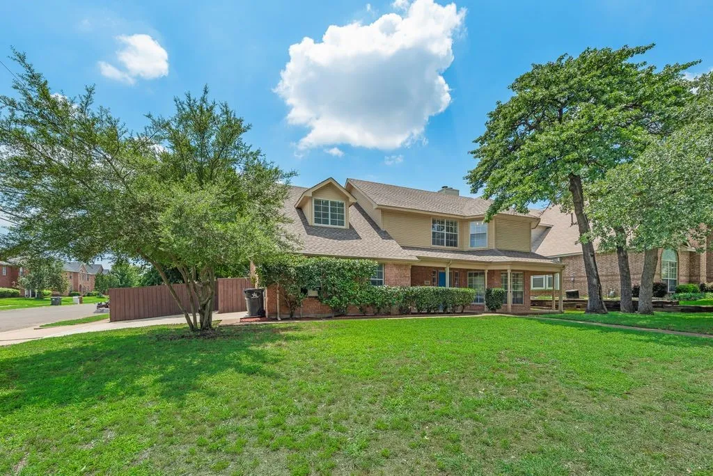 Traditional-style home featuring a brick and stucco exterior, dormer windows, and a covered porch