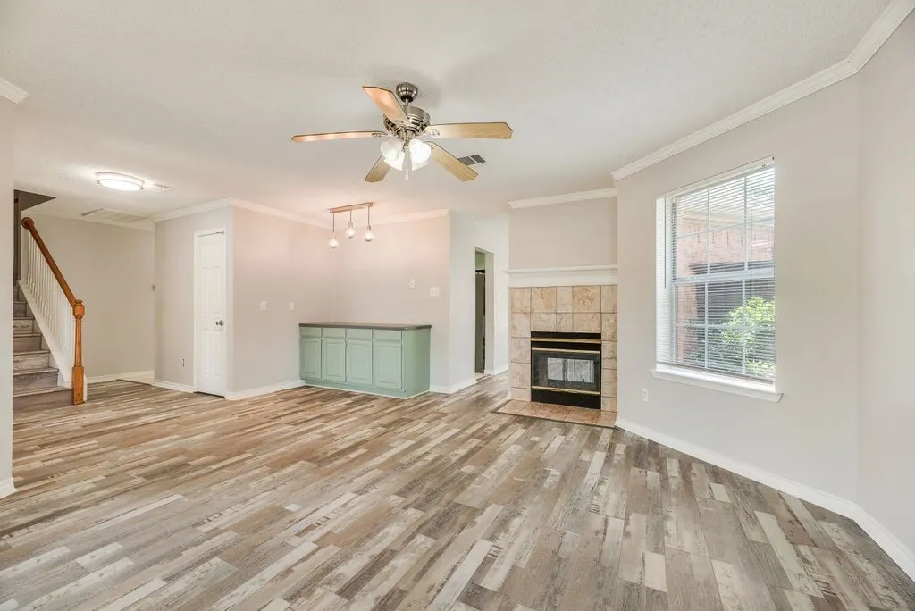 Spacious interior featuring wood-finish flooring, a tile-surround fireplace, and a built-in cabinetry unit
