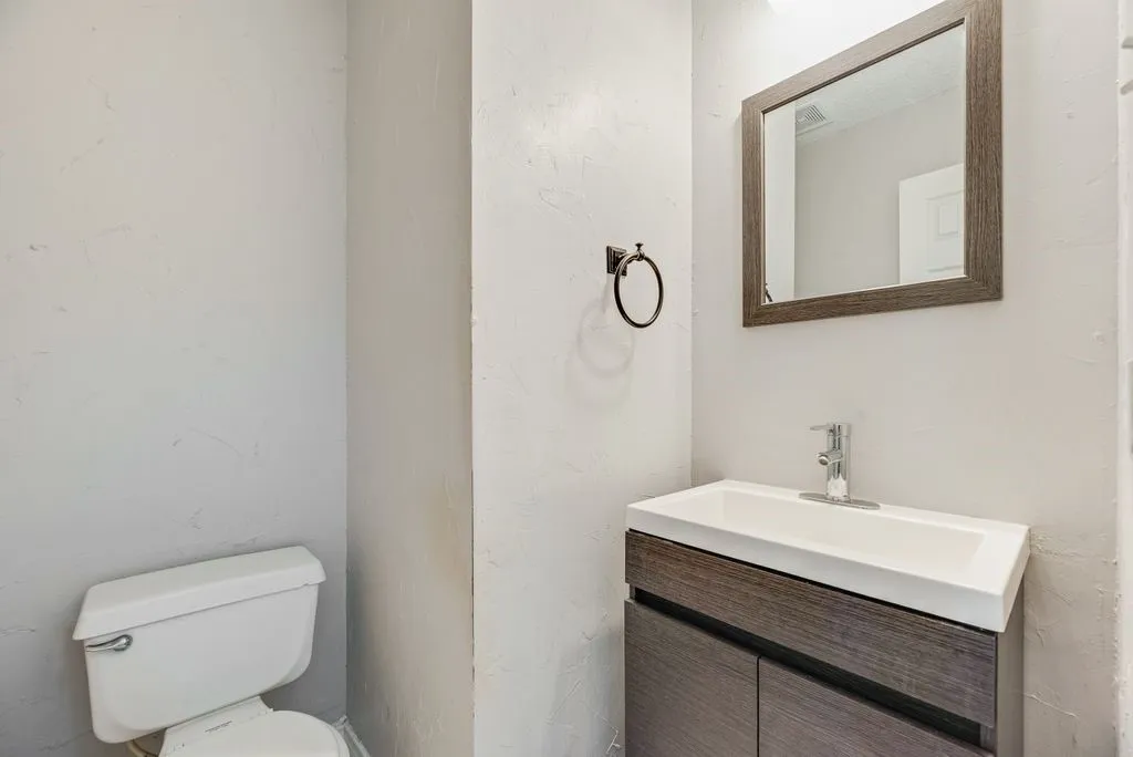 Modern vanity with a wood-finish cabinet, integrated white sink, and chrome faucet