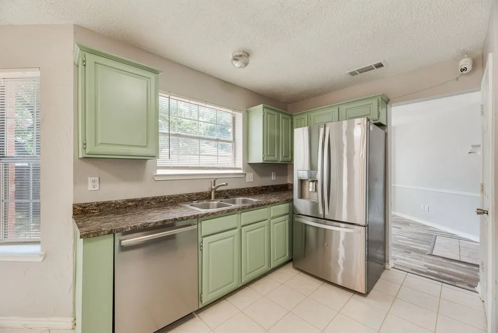 Kitchen featuring light green cabinetry, granite-finish countertops, and white tile flooring