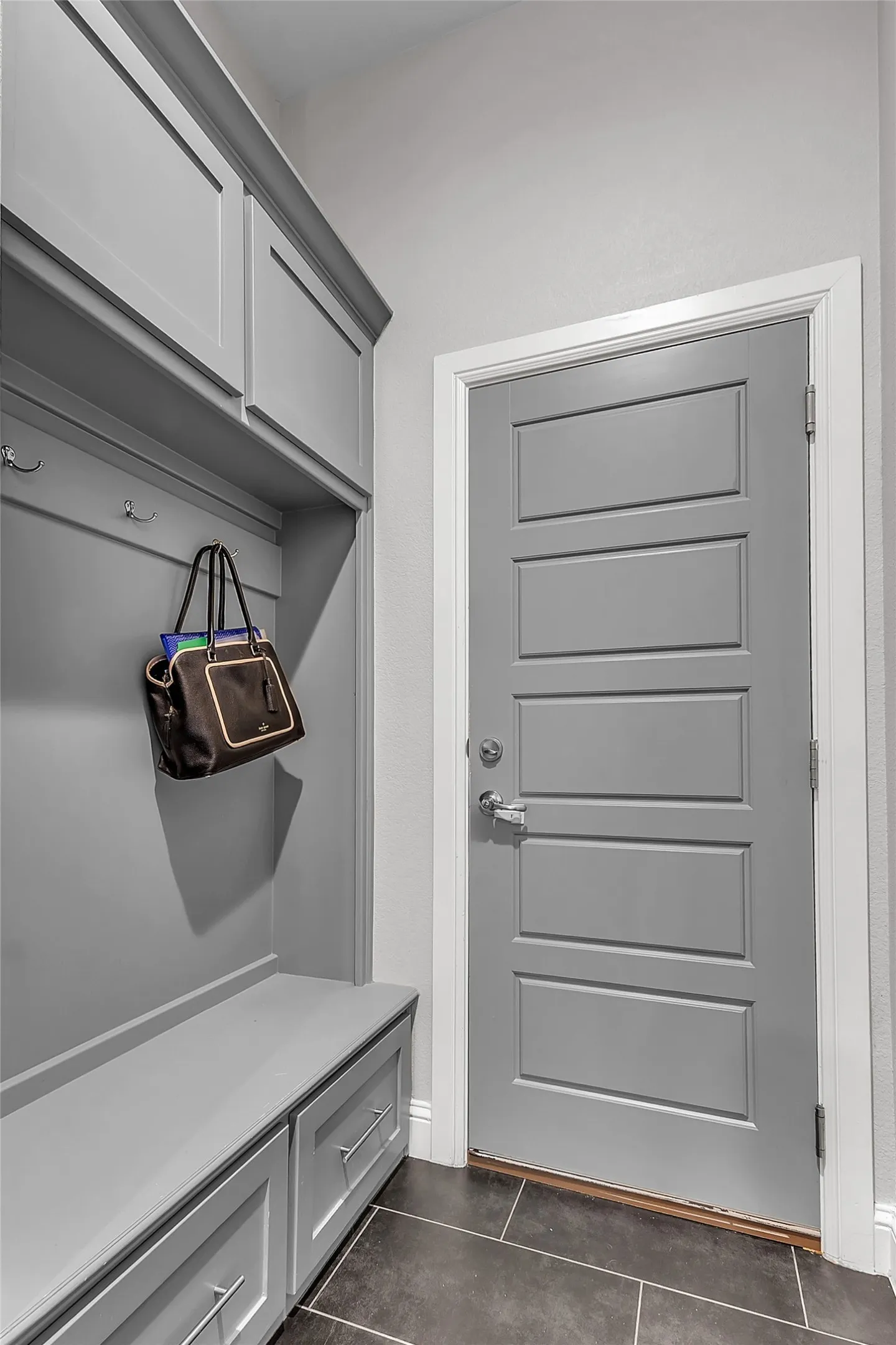 Built-in mudroom just off the garage featuring bench with upper and lower cabinetry for storage