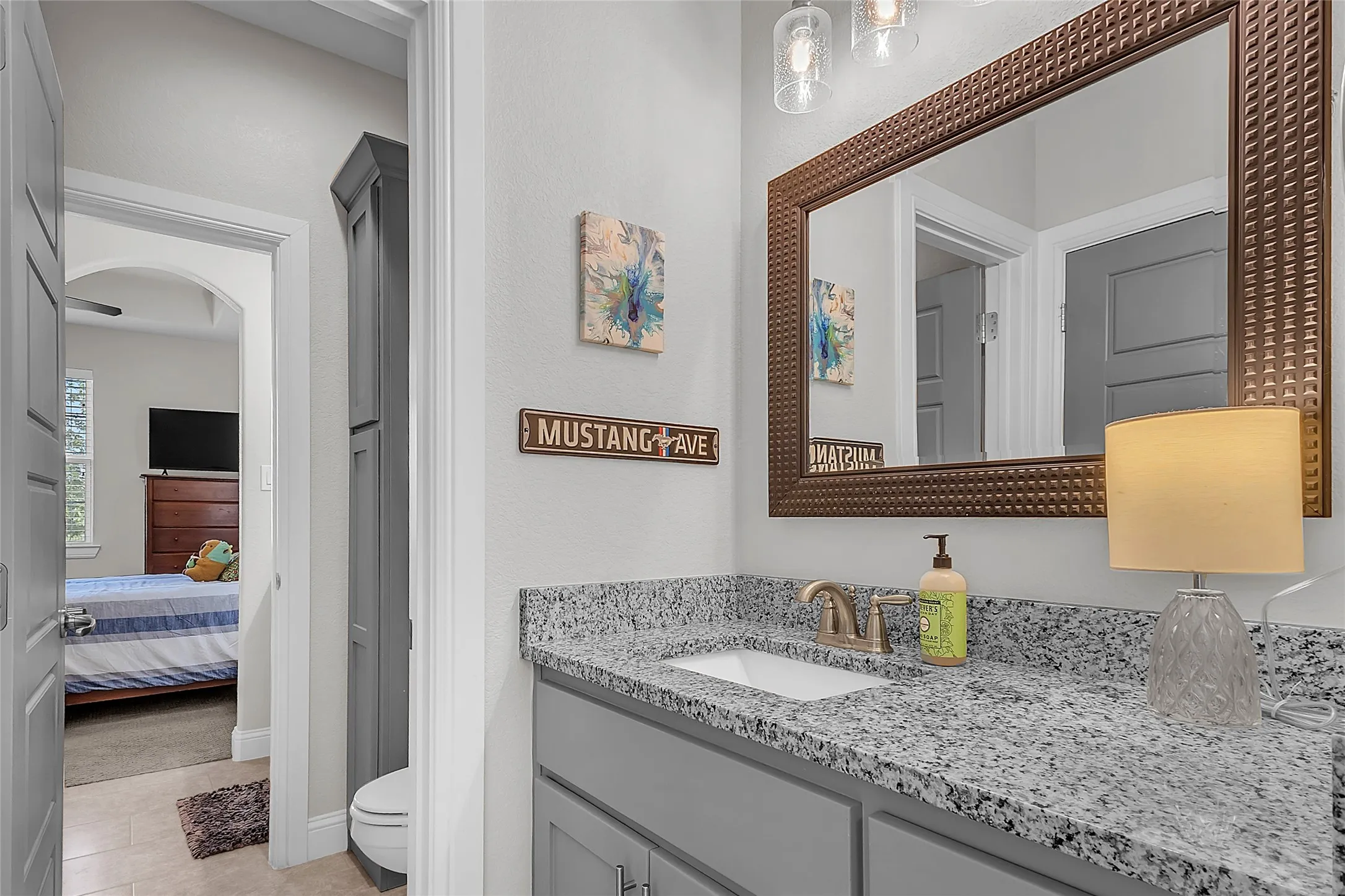 Jack & Jill Bathroom featuring a linen closet, glass-enclosed shower, granite countertop, framed mirror, brushed nickel finishes and tile flooring