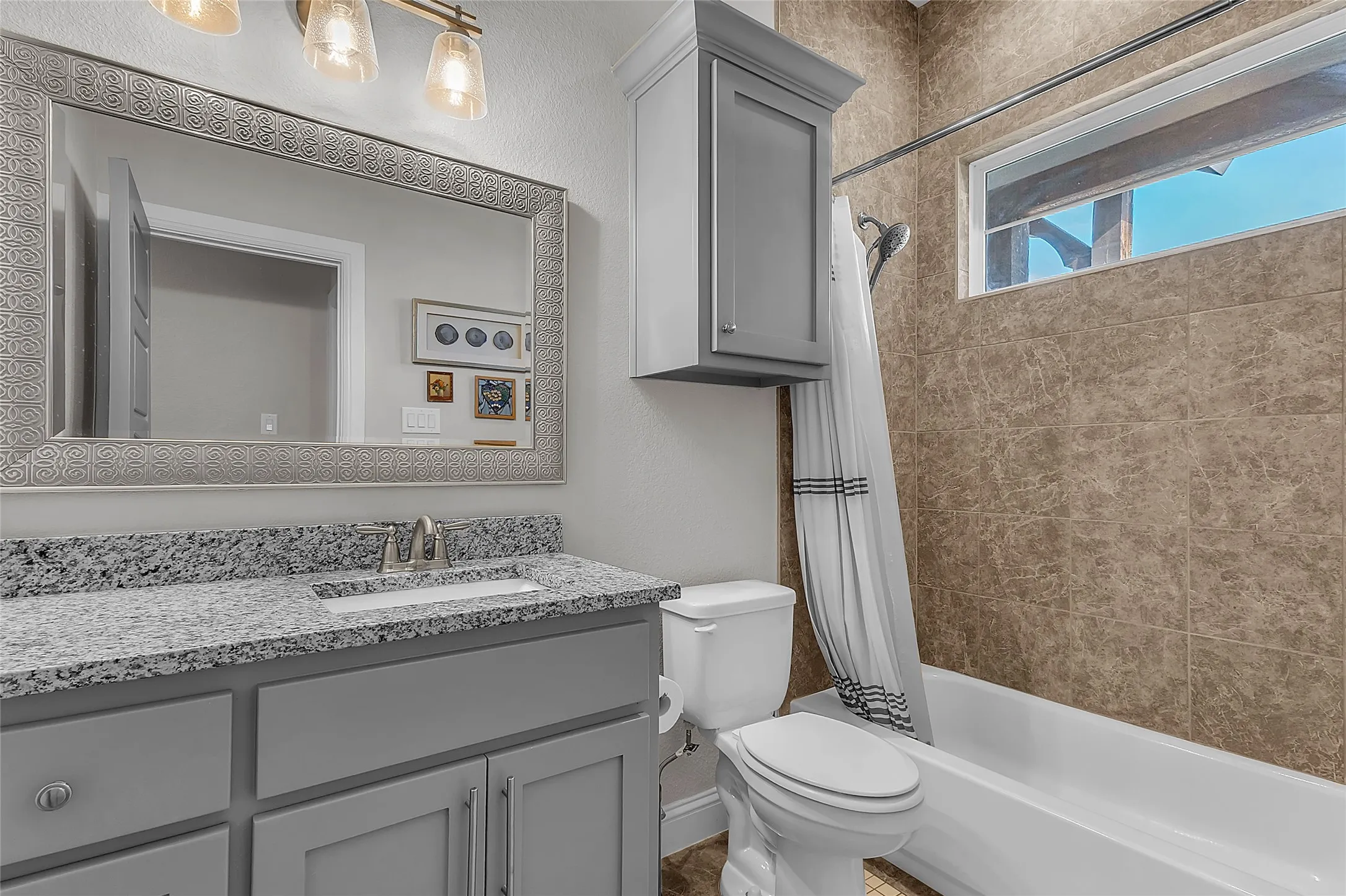 Full bathroom featuring a light gray vanity with a granite countertop and shower/tub combo